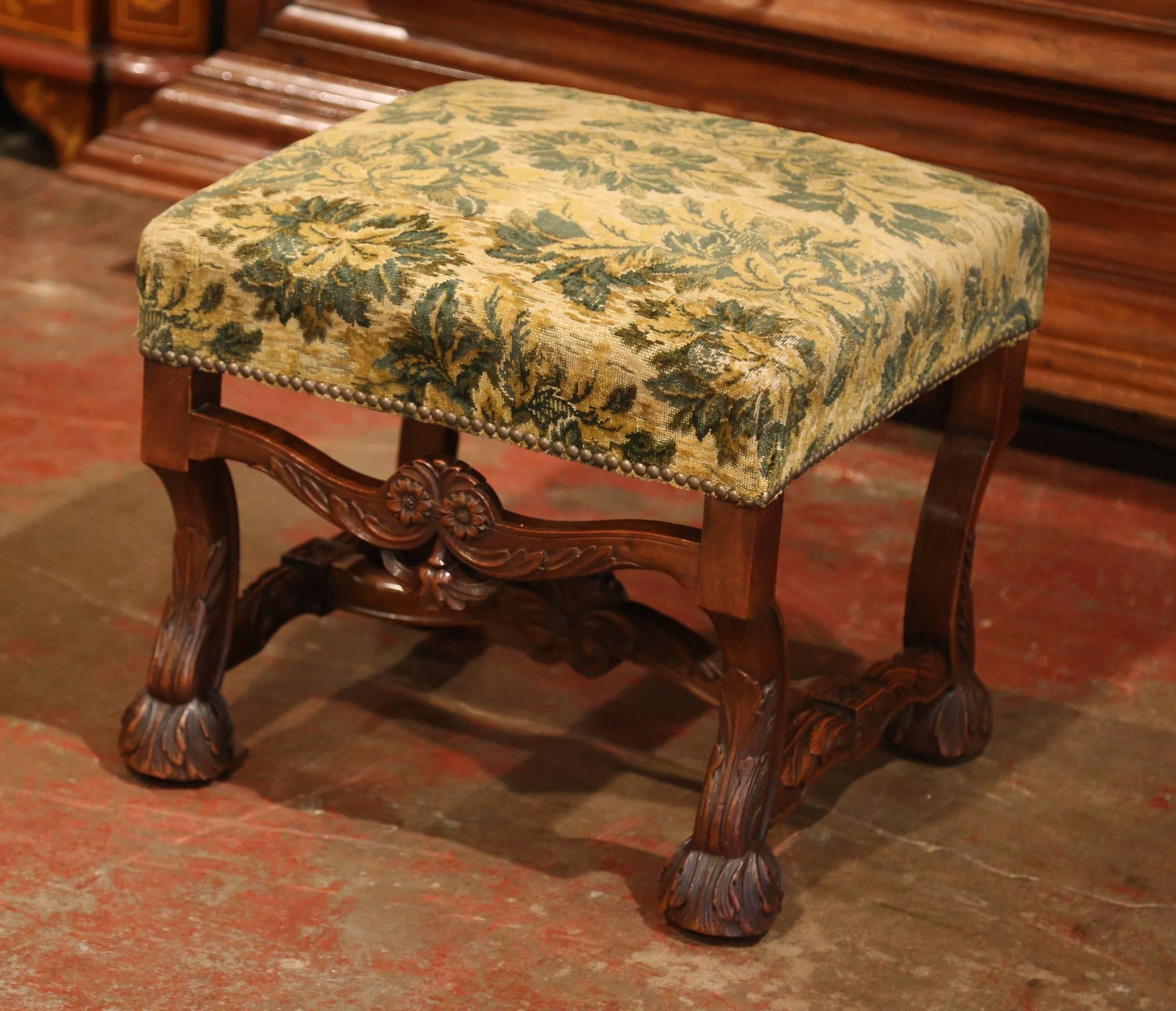 Elegant antique stool from southwest France; crafted circa 1870, the fruit wood stool features four carved scrolled legs with claw feet, acanthus leaves, flowers, and a curved stretcher with center shell. The stool has an old beige and green velvet