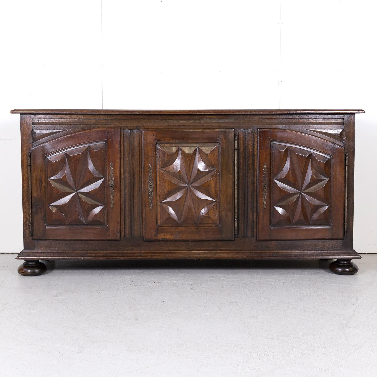 19th century French Louis XIII style enfilade handcrafted by Breton artisans, circa 1890s. A handsome Renaissance style buffet having a solid oak case with a beveled edge rectangular top above three carved walnut doors. All doors feature typical