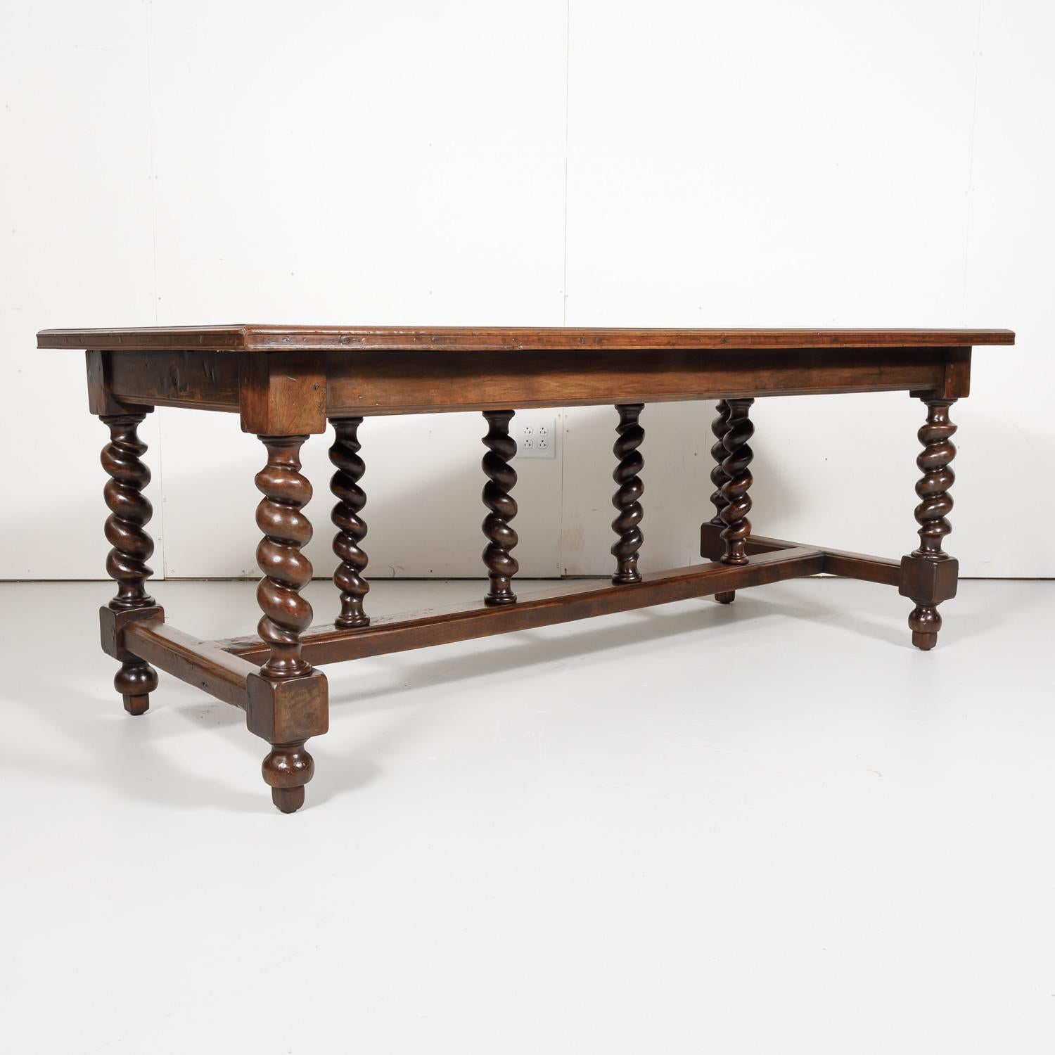 19th century French Louis XIII style barley twist farm table handcrafted in Lyon of solid walnut, circa 1890s. This handsome table has a rectangular inset plank top raised on four barley twist legs joined by an H-stretcher with three vertical barley