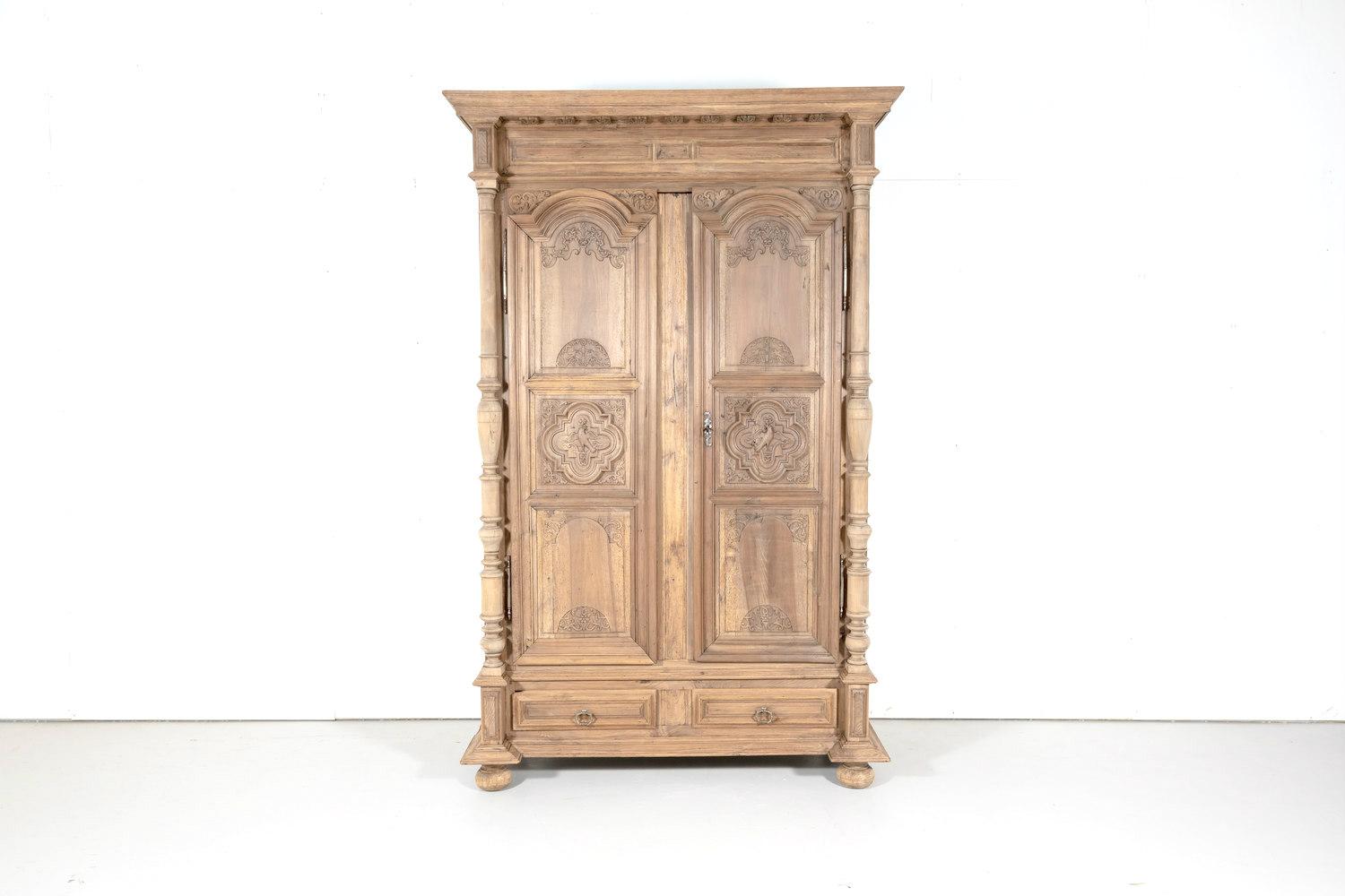 19th century French Louis XIII style armoire handcrafted in walnut by master artisans in Lyon, circa 1880s. The stepped out cornice of this handsome bleached armoire has stylized dentil moulding and sits atop a carved frieze. The raised and recessed