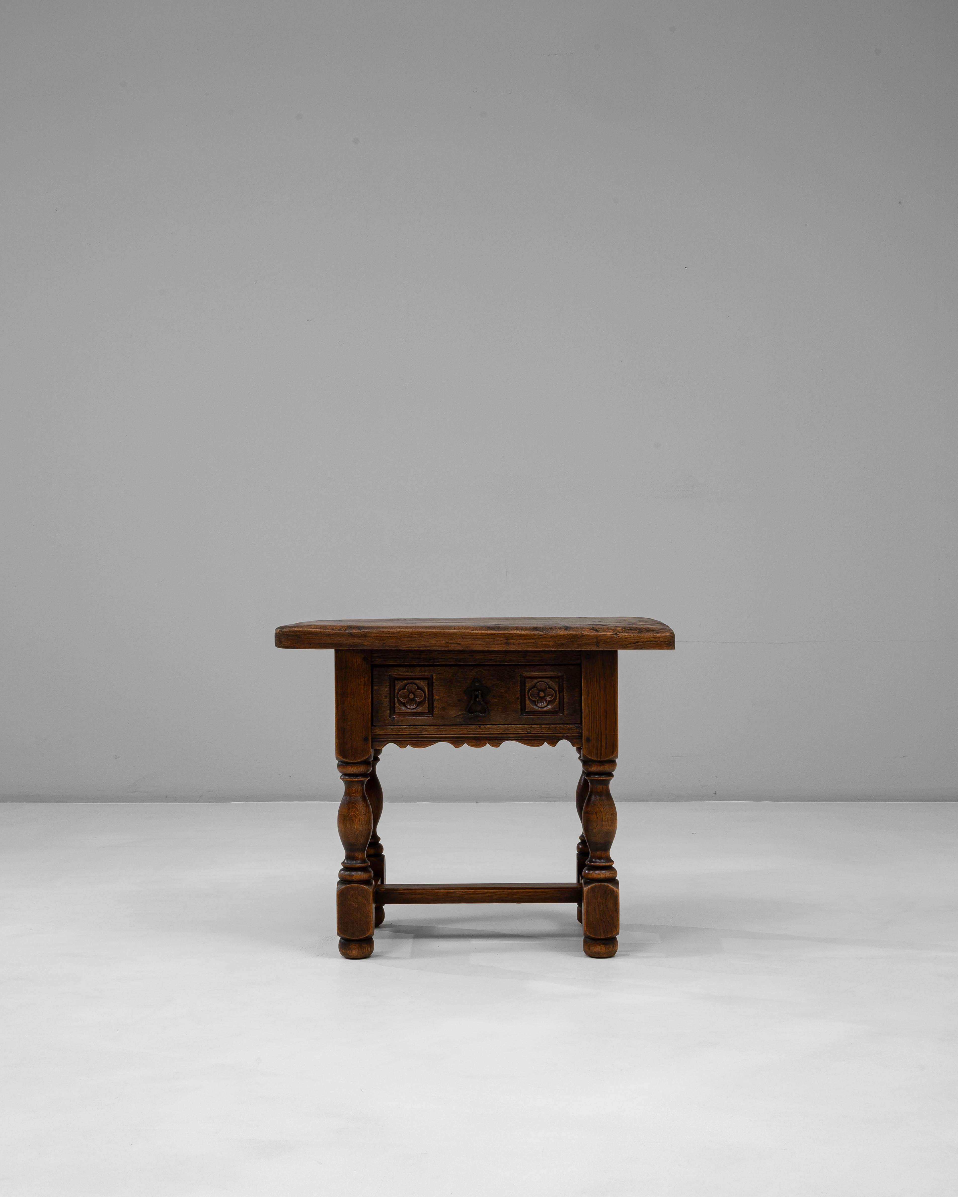 This 19th-century French side table reflects the enduring craftsmanship of the Louis XIII style, characterized by its robust form and sculpted detailing. Constructed from richly patinated oak, it features a single drawer adorned with hand-carved