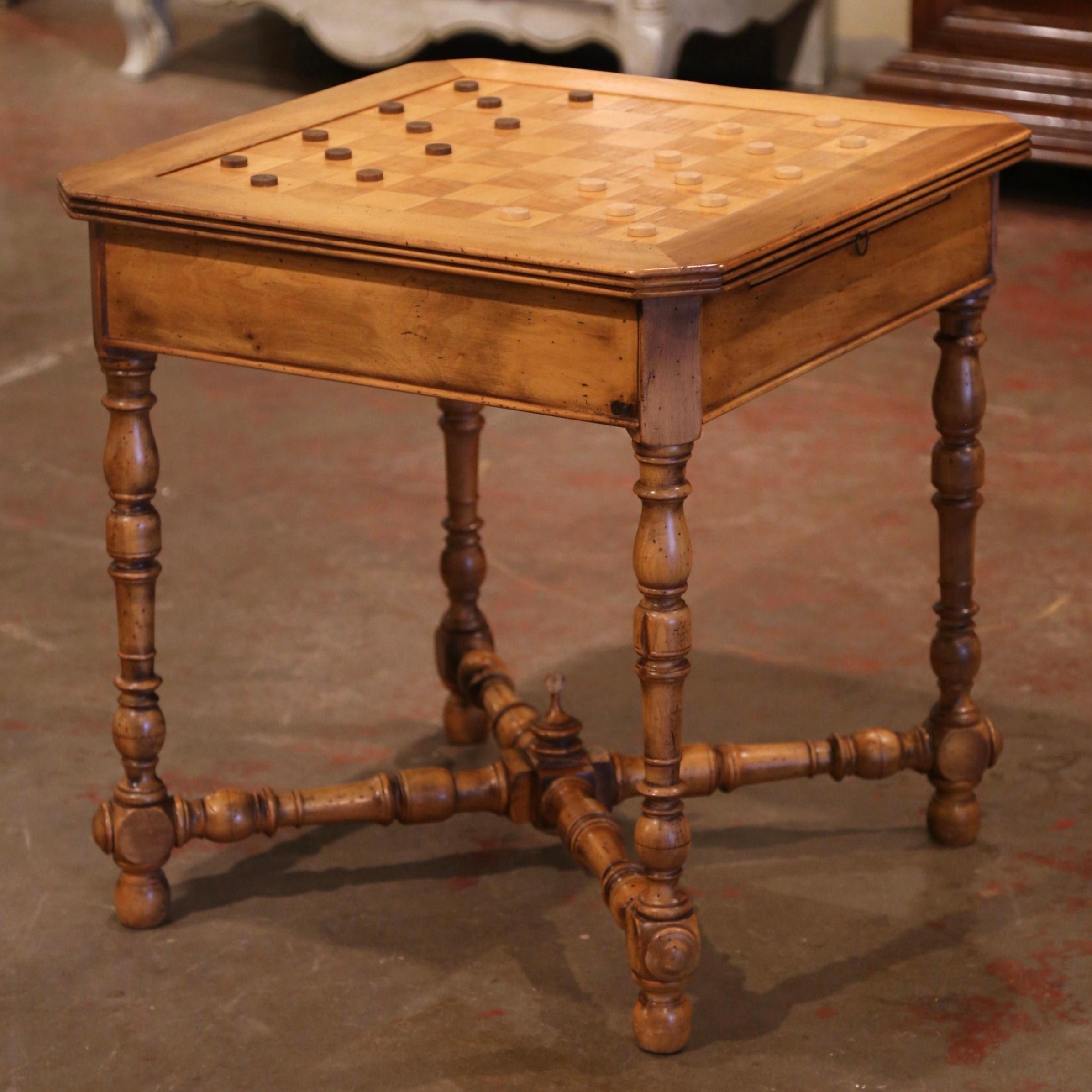 Crafted in southern France circa 1870, the antique game table stands on four elegant turned legs connected with a bottom X-stretcher embellished with a central finial. The multi function surface features a chess or checker board on one side and a