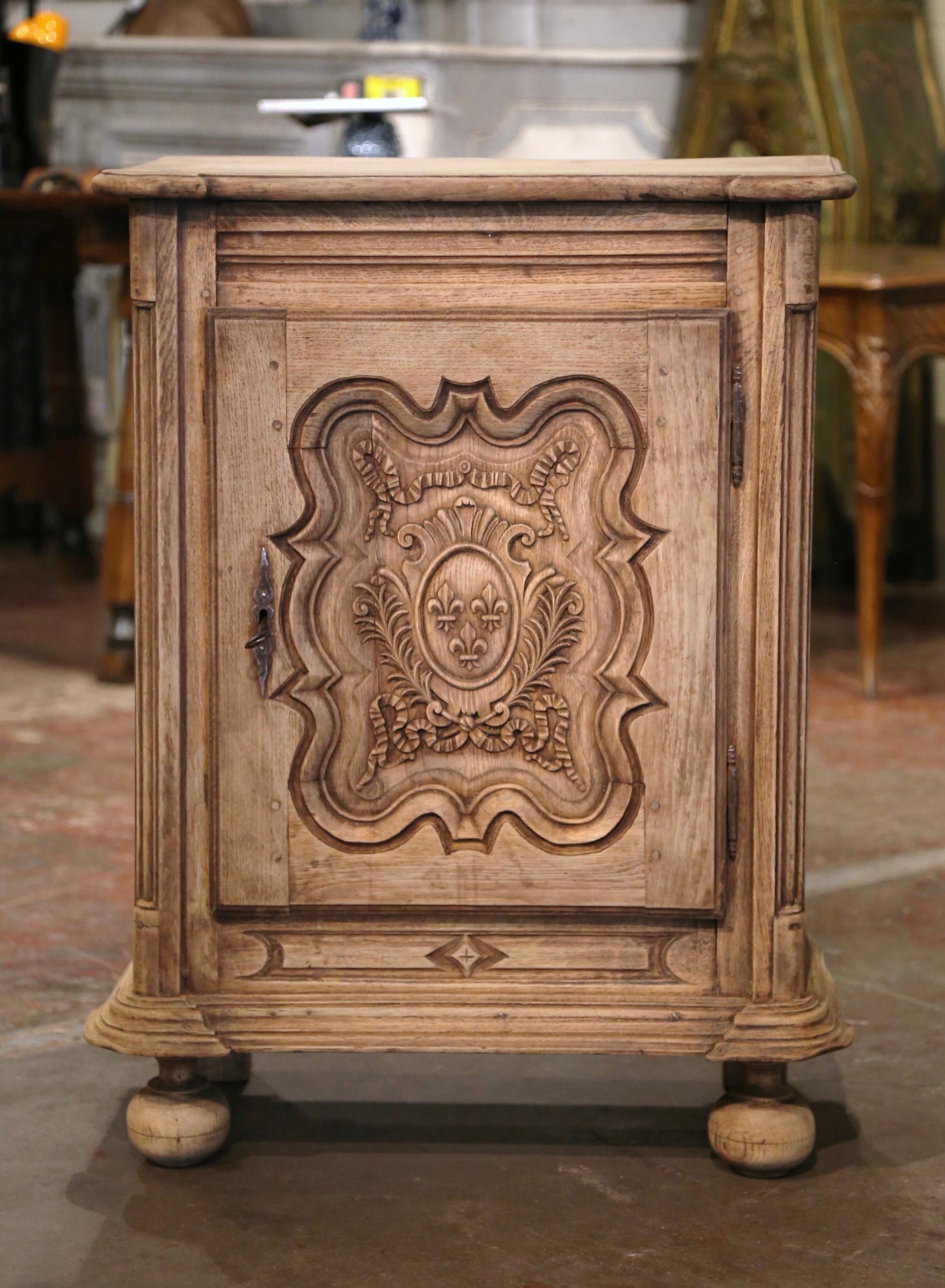 This elegant antique jelly cabinet was crafted in Normandy, circa 1870. Built in oak wood, the small buffet stands on bun feet over a molded plinth base decorated with geometric motif. The provincial confiturier is fitted with a center raised panel