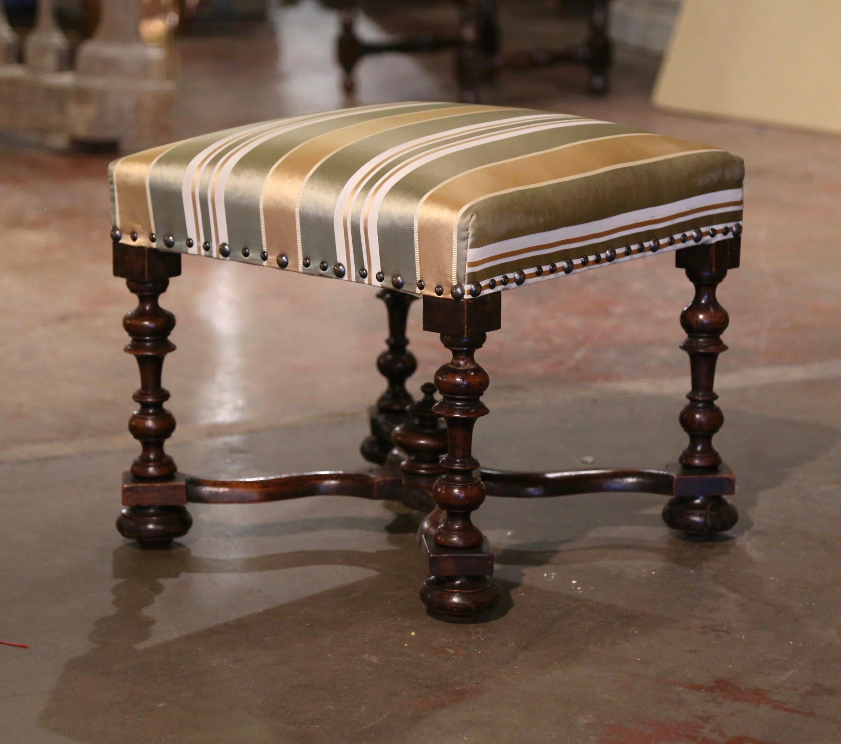 Decorate a den, living room or master bedroom with this elegant antique stool. Crafted in southern France circa 1870 and almost square in shape, the elegant ottoman stands on turned legs ending with bun feet over a X serpentine stretcher decorated