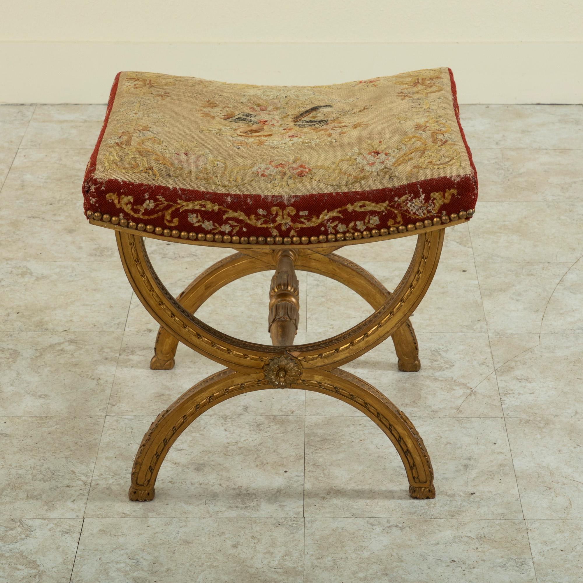 This mid-nineteenth century Louis XIV style vanity stool or bench features a gilt wood base formed by opposing half circles. The legs are detailed with acanthus leaves, a twisted ribbon motif, and an overlapping quatrefoil pattern. A stretcher with