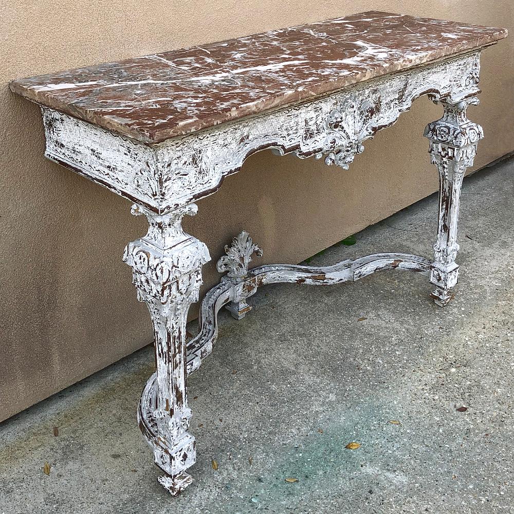 19th century French Louis XIV marble-top console is a study in grandeur, with elaborately sculpted legs, stretchers and apron rendered in the Baroque style of which the Sun King was so enamored. The patinaed painted finish enhances the bold carved