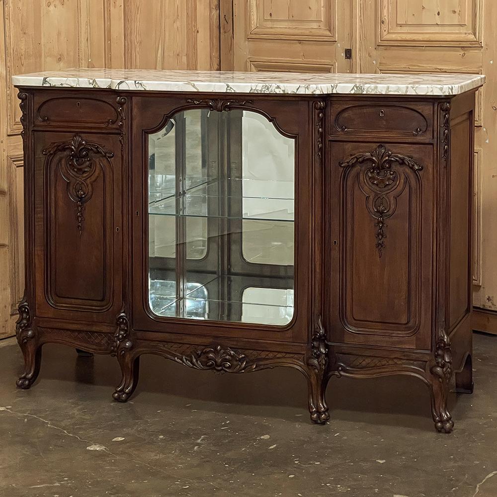 19th Century French Louis XIV marble top walnut display buffet for those who wish to possess an exquisitely rendered, beautifully styled focal centerpiece to a room that performs multiple critical functions! Styled in the manner of the Sun King, its