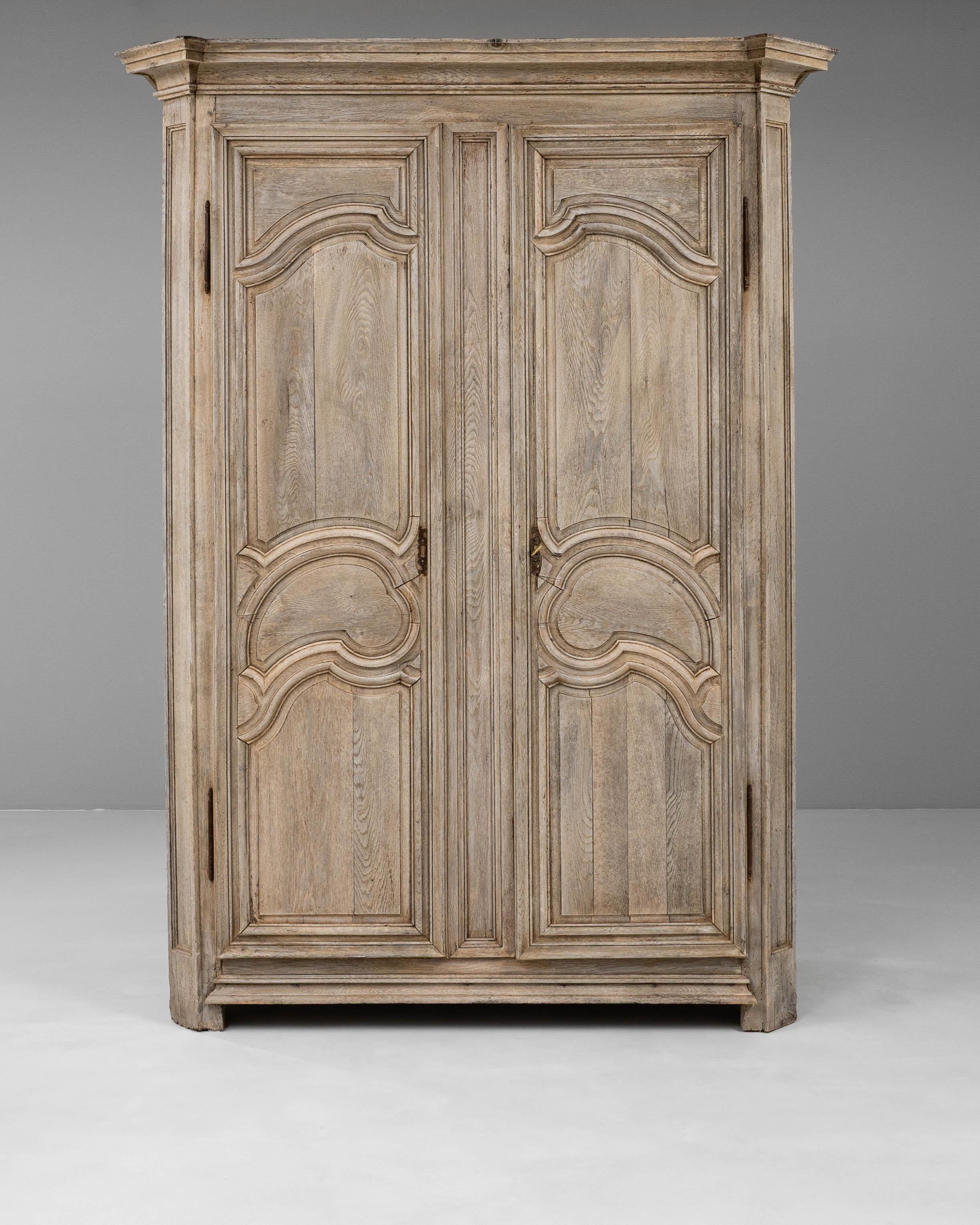 This 19th Century French Louis XIV oak cabinet showcases the grandeur and craftsmanship associated with the period. Constructed from richly grained oak, the piece features bold paneled doors with carved geometric motifs that emphasize symmetry and