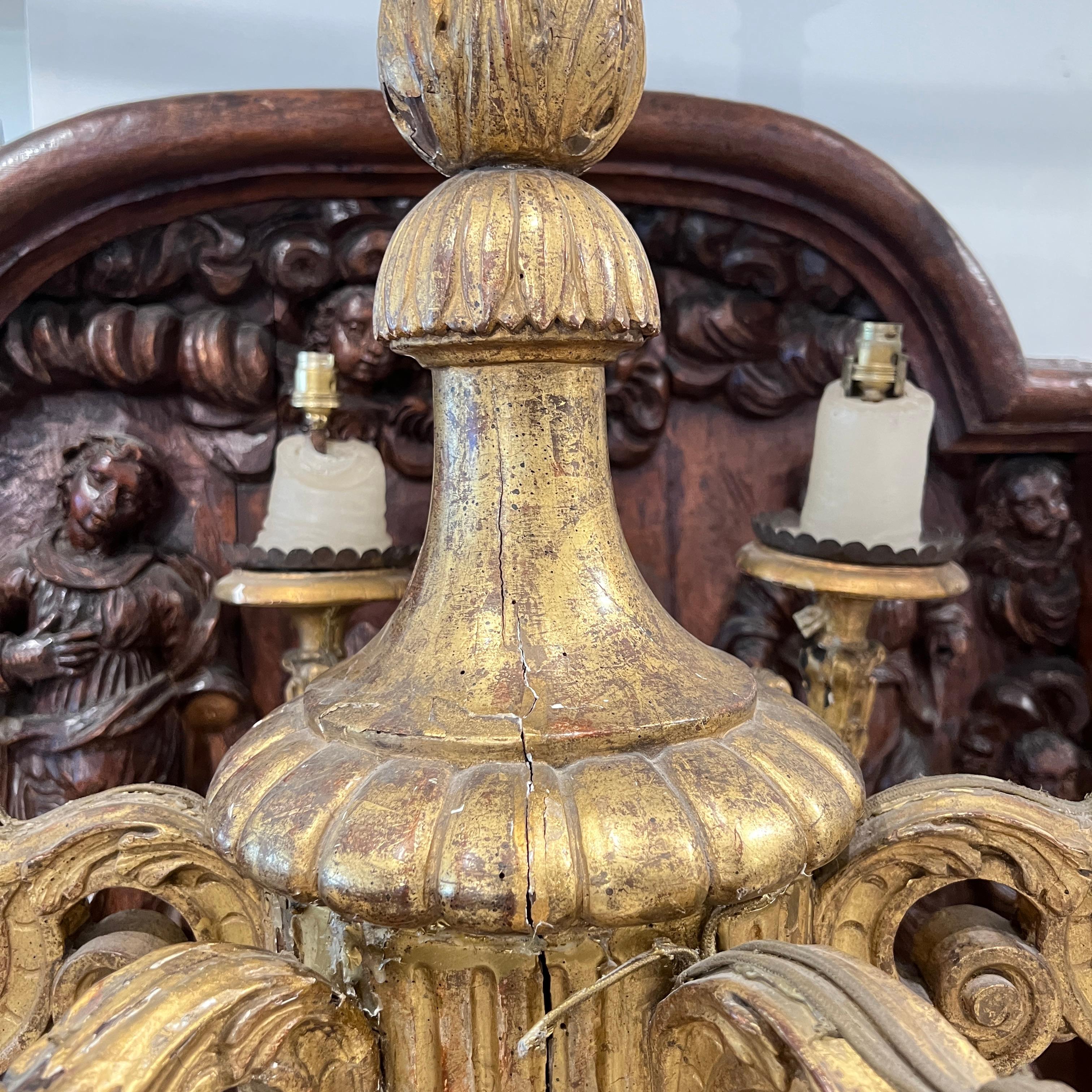 Ce lustre majestueux en bois sculpté de style Louis XIV présente des proportions classiques audacieuses, des volutes spectaculaires et de riches détails dorés ou peints, reflétant la grandeur et la symétrie de l'esthétique baroque du Roi-Soleil.