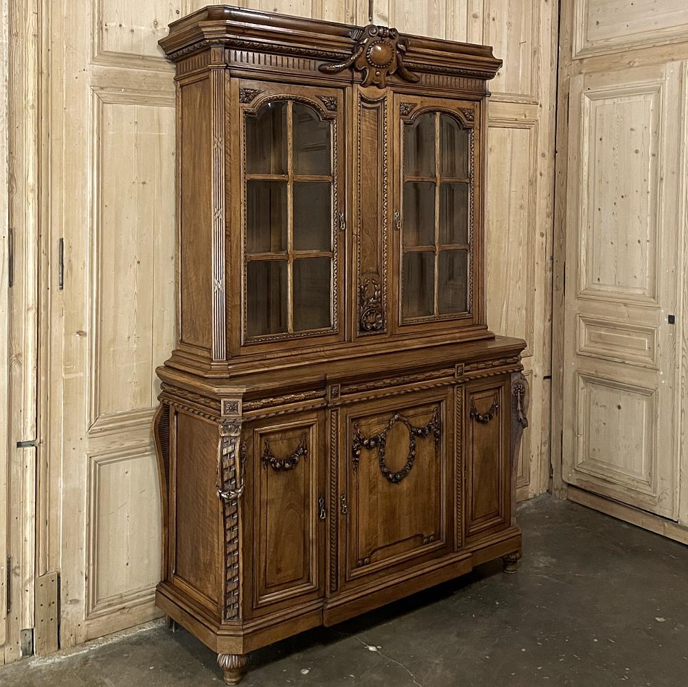 19th century French Louis XIV walnut bookcase is a masterpiece of art, architecture and style! Rendered in sumptuous French walnut, considered the finest indigenous wood from the European continent, it features a bold crown centered with a