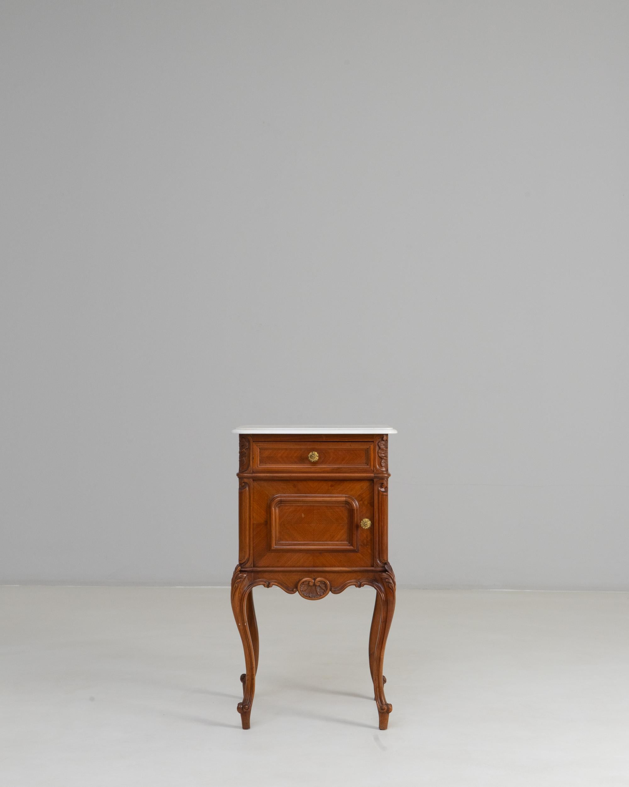 19th Century French Louis XV Bedside Table With Marble Top. This refined bedside table captures the graceful elegance of Louis XV design, highlighted by its flowing cabriole legs, delicate carvings, and warm wood tones. The white marble top adds a