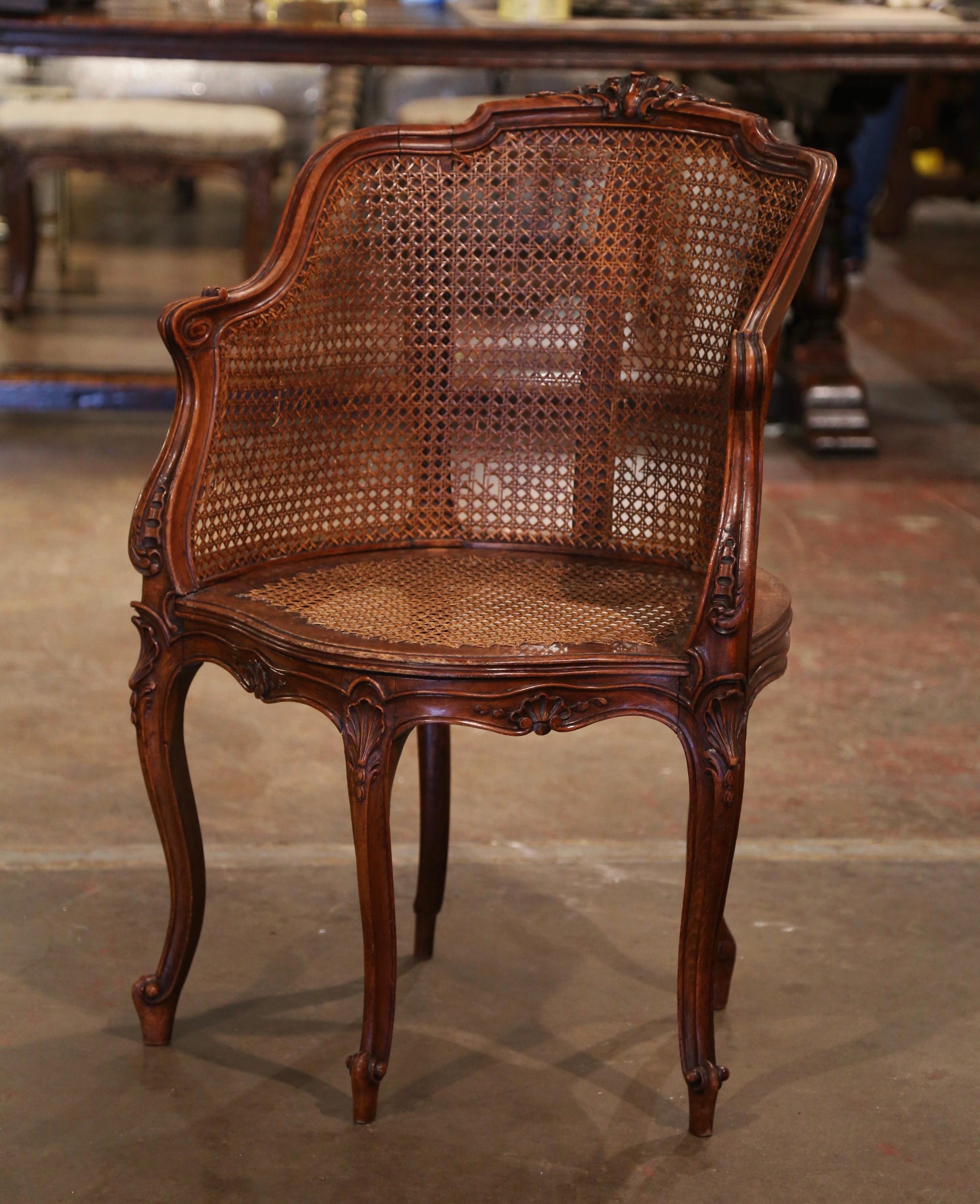 Decorate a study or office with this elegant antique desk armchair. Crafted in Provence, France, circa 1880, the corner chair has an arched cane back decorated with a shell motif at the pediment. The traditional desk chair stands on five cabriole