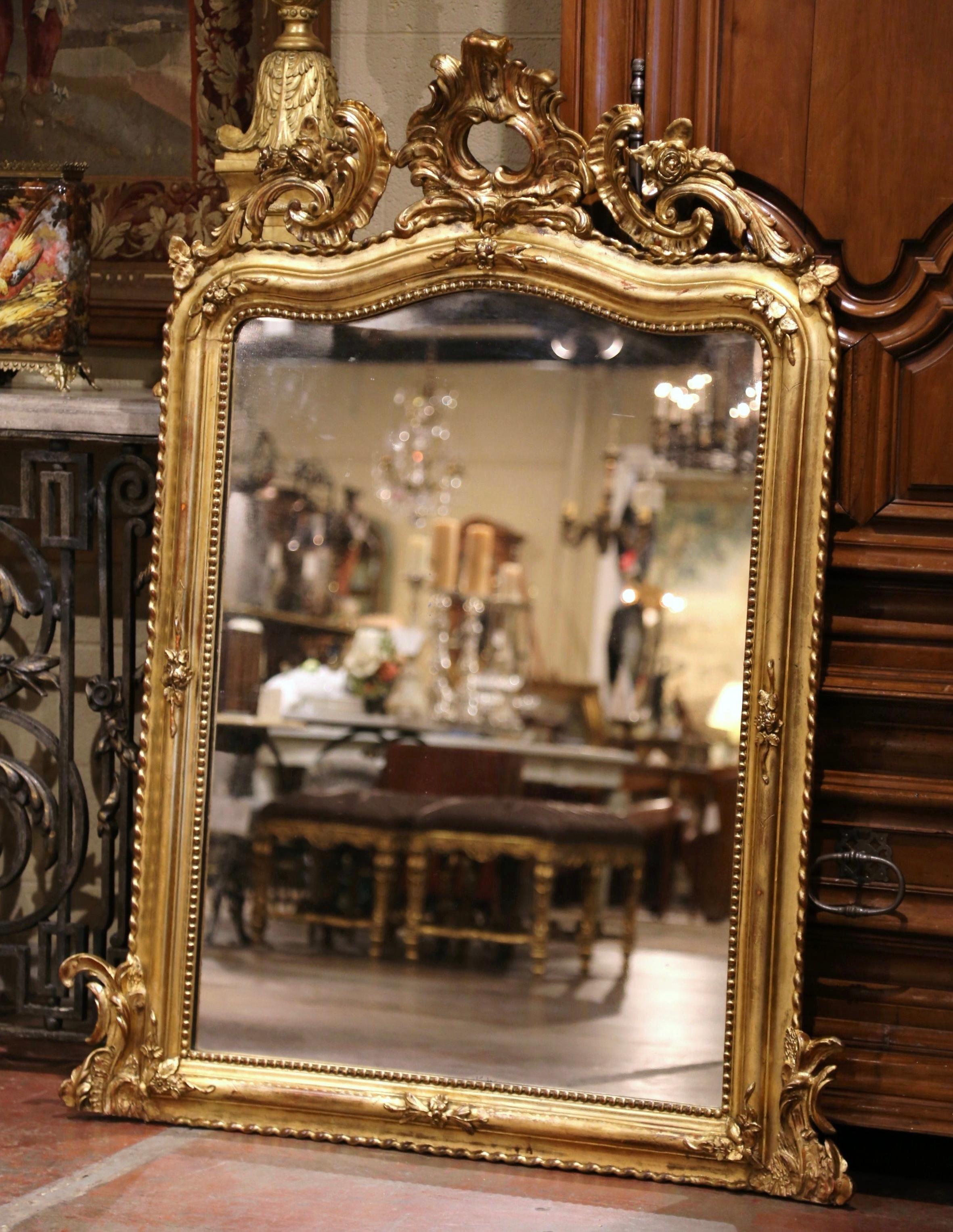  Vesti un caminetto con questo elegante specchio antico intagliato e dorato. Realizzato in Francia intorno al 1860 e alto più di un metro e mezzo, il grande specchio con piano ad arco e serpentino è decorato con un cartiglio a conchiglia traforato