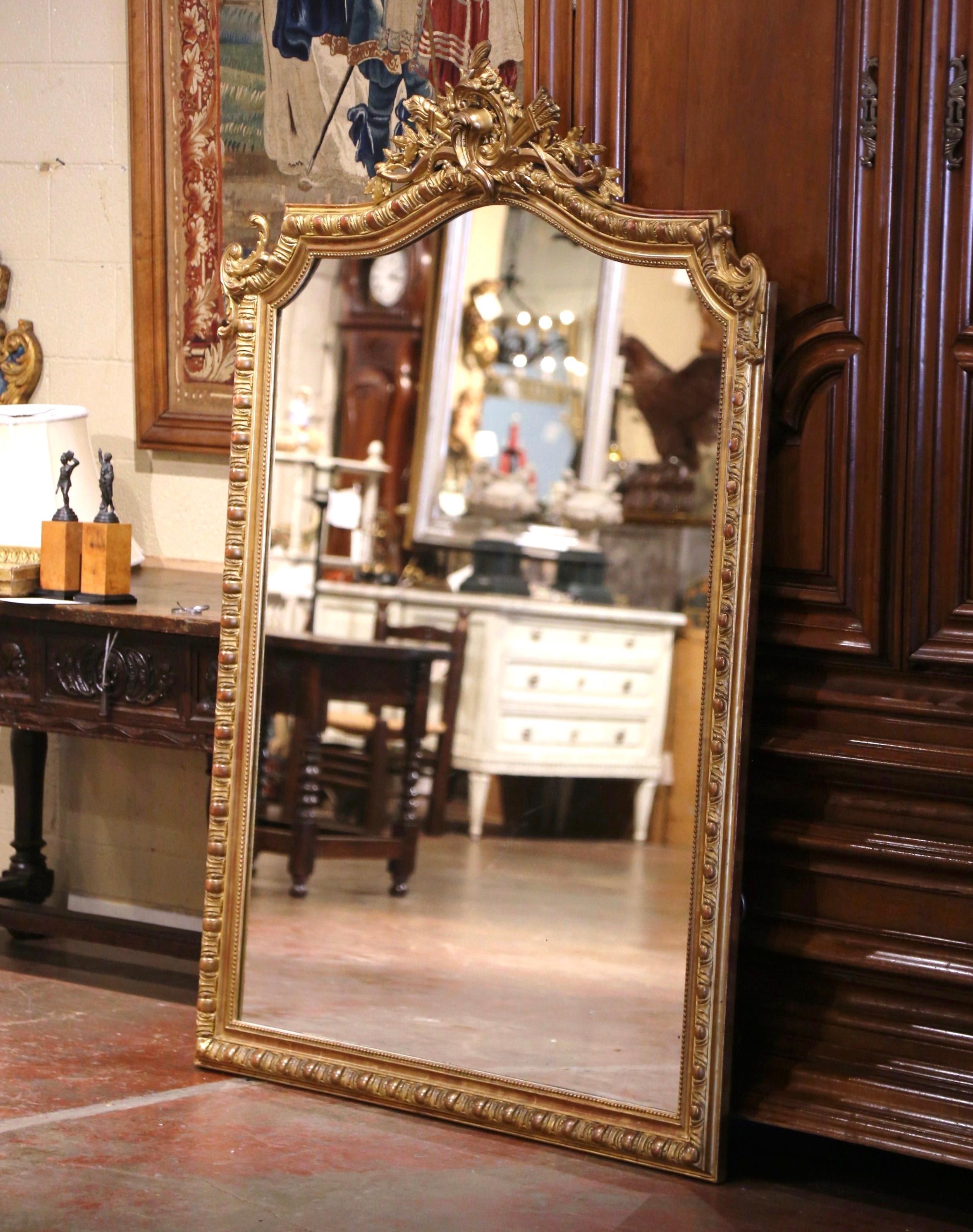 
 Realizzato in Francia intorno al 1870 e alto quasi due metri, il grande specchio dorato antico presenta un piano ad arco e serpentino che mostra un sontuoso stemma in alto rilievo ornato da foglie d'acanto e motivi floreali, impreziosito da un