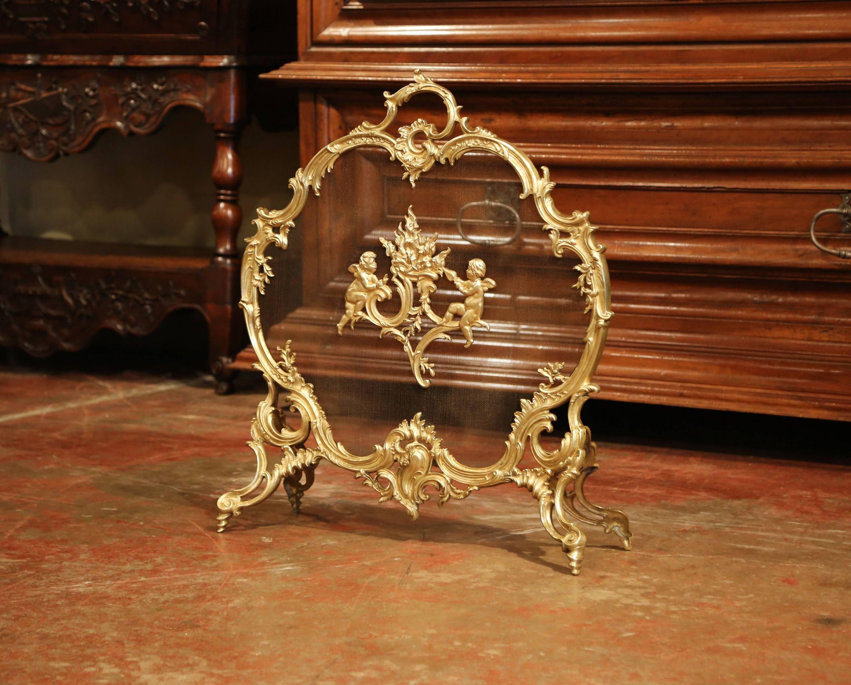 Decorate your fireplace with this antique Rococo bronze screen from France. Crafted circa 1870, the cartouche shaped screen sits on four scroll feet and features Louis XV style motifs including asymmetrical foliage swaths and mythological cherubs on