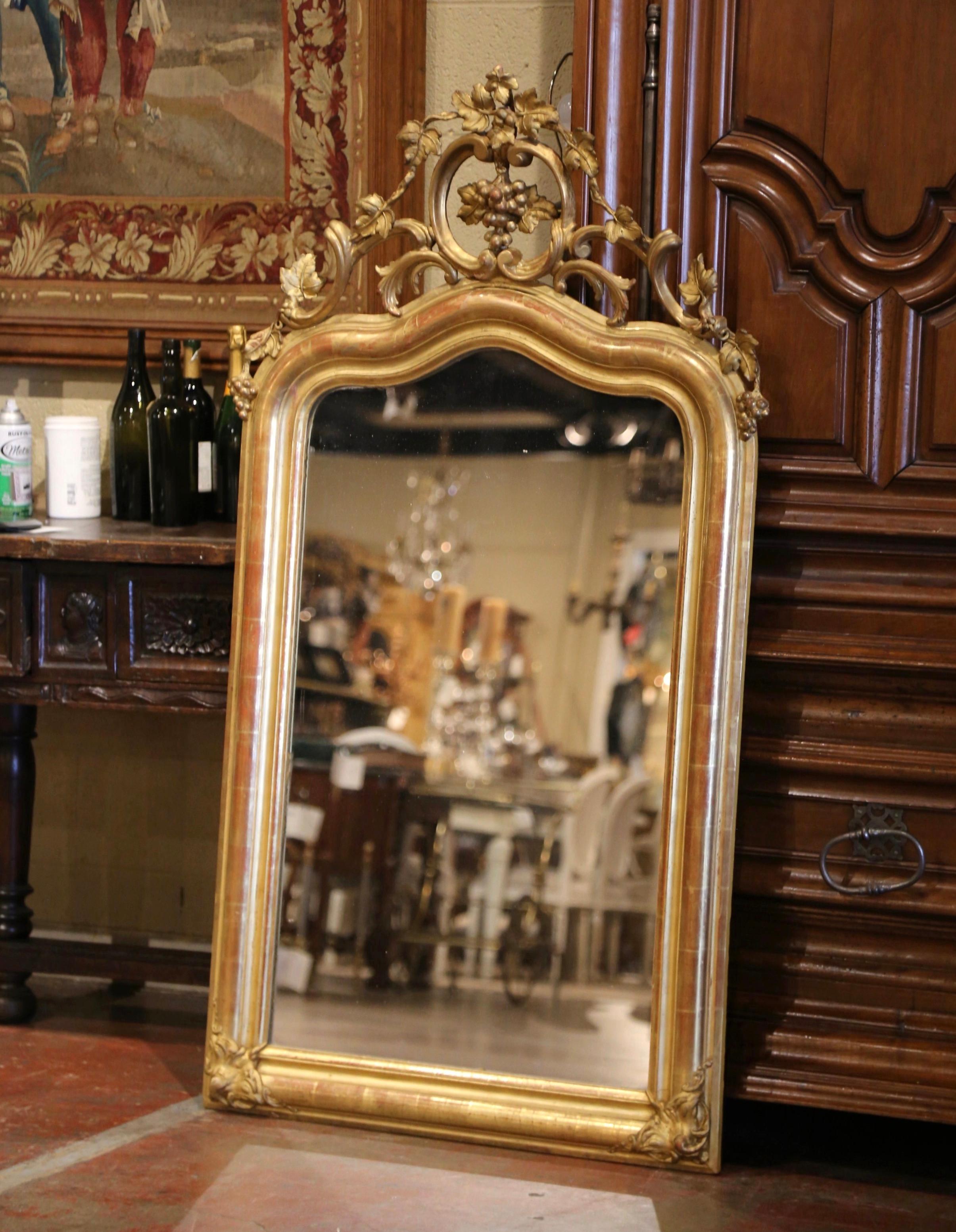 Eleganza e raffinatezza: questo elegante specchio dorato d'epoca è l'ideale per arredare una toilette o una cantina. Realizzato in Francia, intorno al 1870, il frontone traforato è decorato con un grappolo d'uva e una vite, affiancati da foglie e