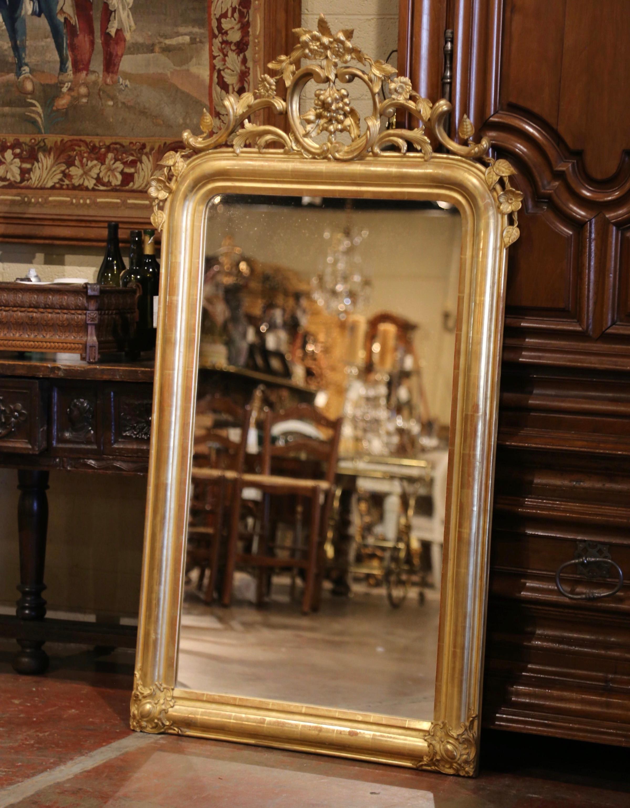 Decorate a powder room or a wine cellar with this elegant antique gilt mirror! Crafted in France, circa 1870, the ornate pierced pediment features a bunch of grape and vine decor cartouche, flanked with leaf and vine roots on both sides. The thick