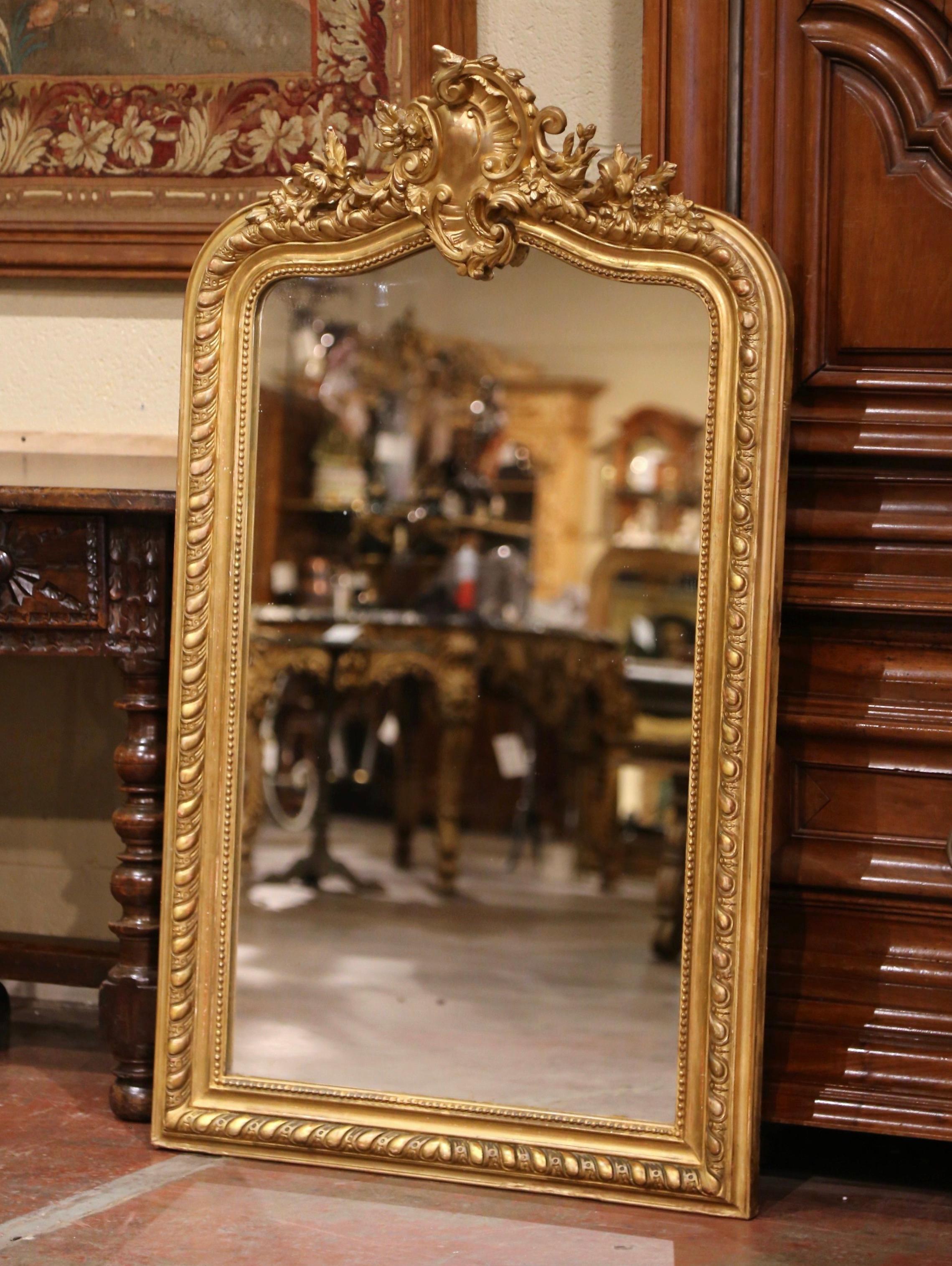 Decorate a powder room or entry with this elegant antique mirror. Crafted in France circa 1870, and curved at the top, the wall mirror is decorated with a hand carved cartouche at the pediment featuring a center shell motif flanked by floral and
