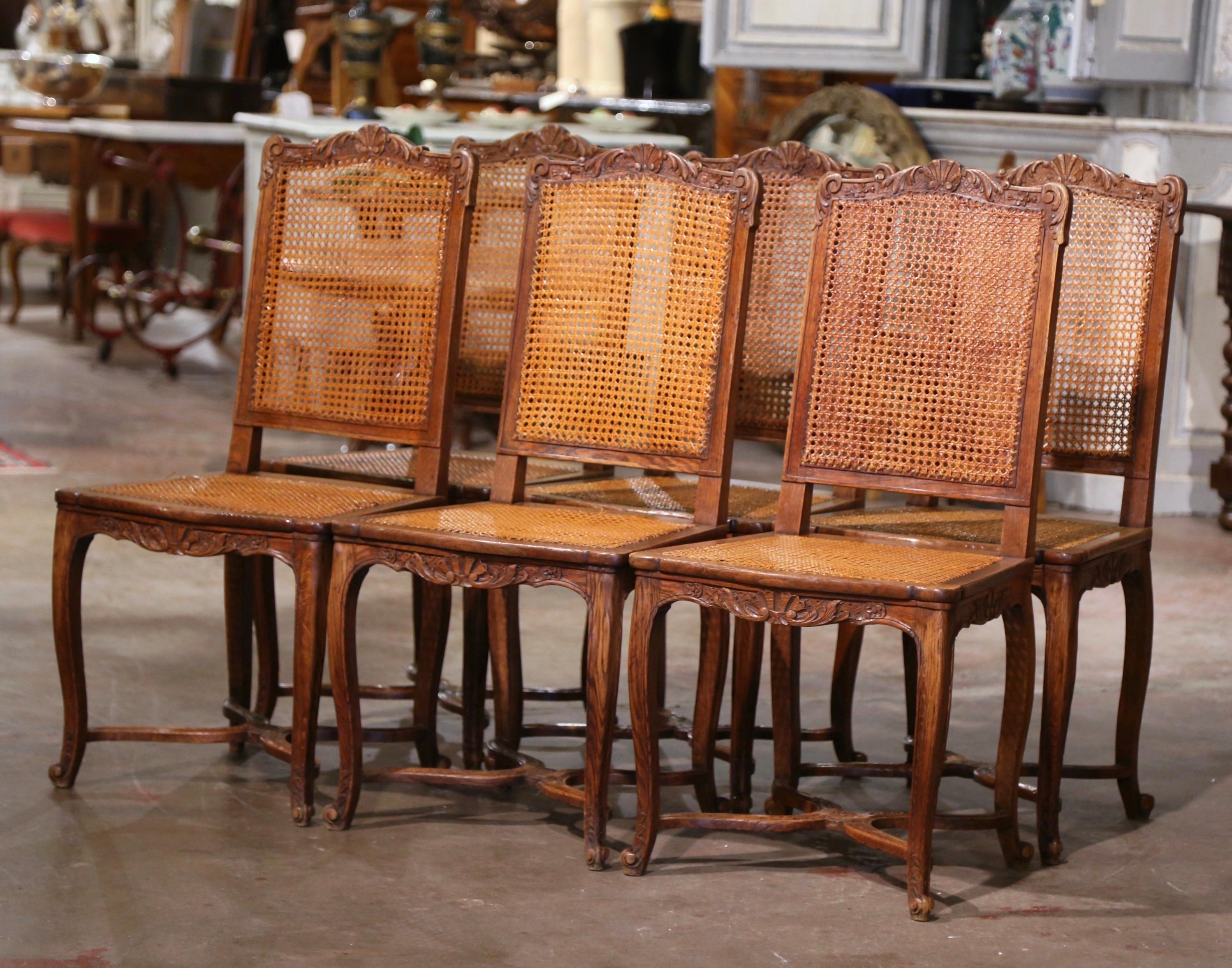 Decorate a dining table with this elegant suite of antique oak side chairs. Crafted in France circa 1880, each dining chair stands on cabriole legs ending with escargot feet over an X bottom stretcher decorated with a floral medallion. Scalloped