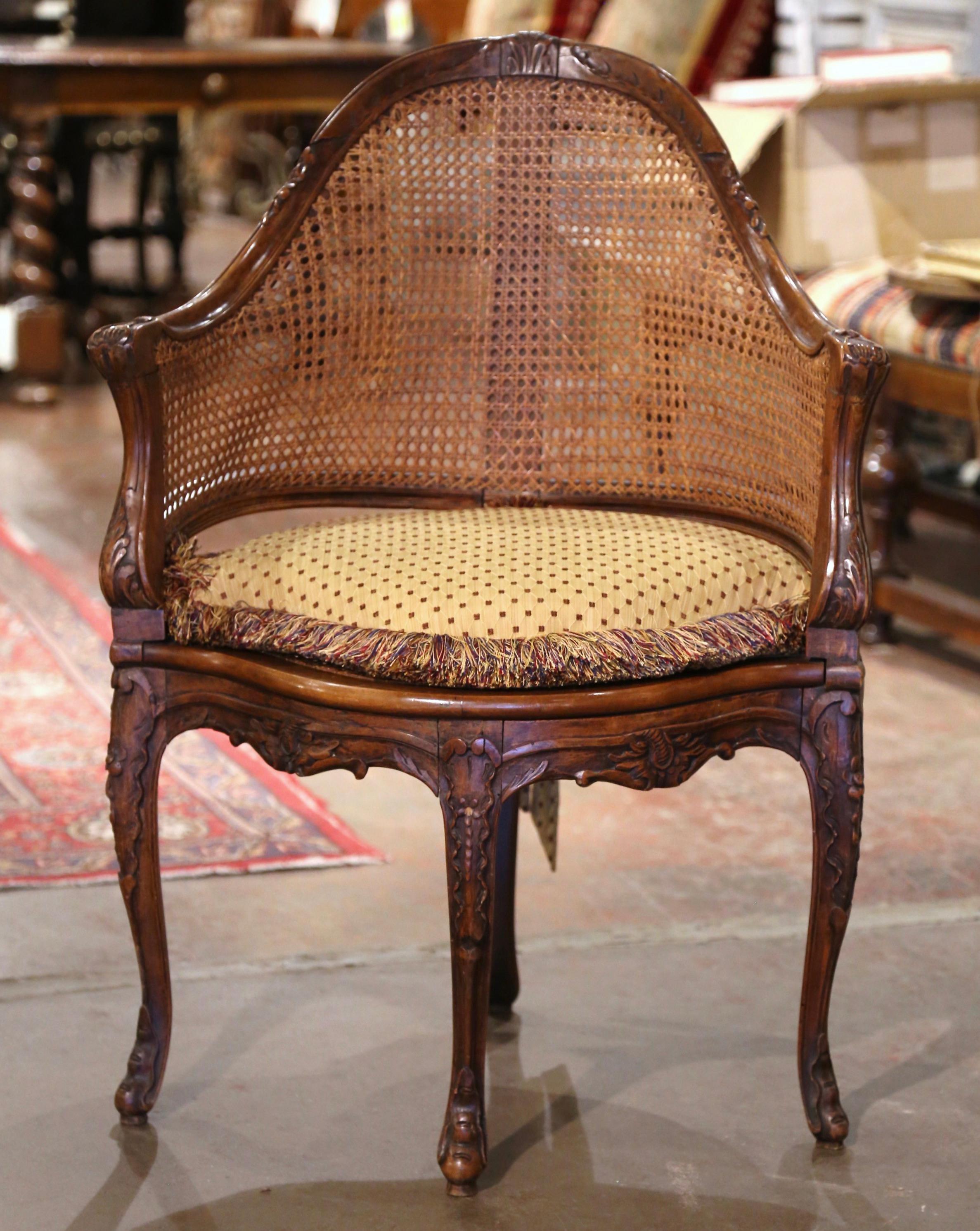 Decorate a study or office with this elegant antique desk armchair. Crafted in Provence, France, circa 1870, the corner chair has an arched cane back decorated at the top with floral motif. The traditional desk chair stands on four carved cabriole