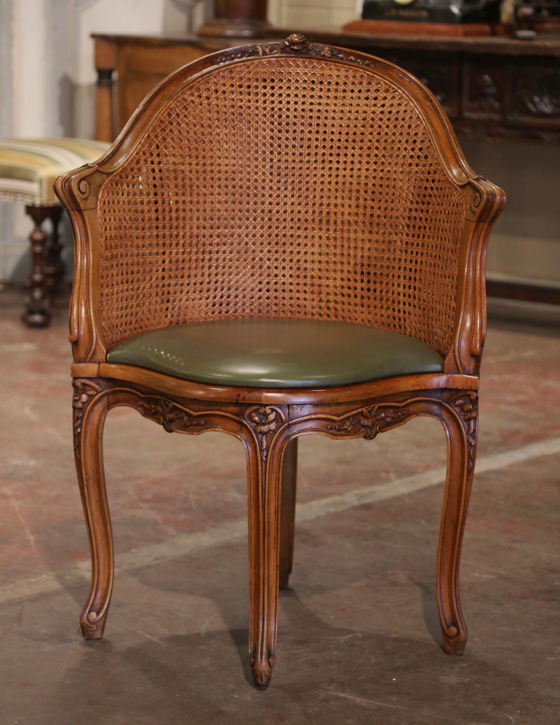 Decorate a study or office with this elegant antique desk armchair. Crafted in Provence, France, circa 1870, the corner chair has an arched  rounded cane back decorated at the top with floral motif. The traditional desk chair stands on four carved