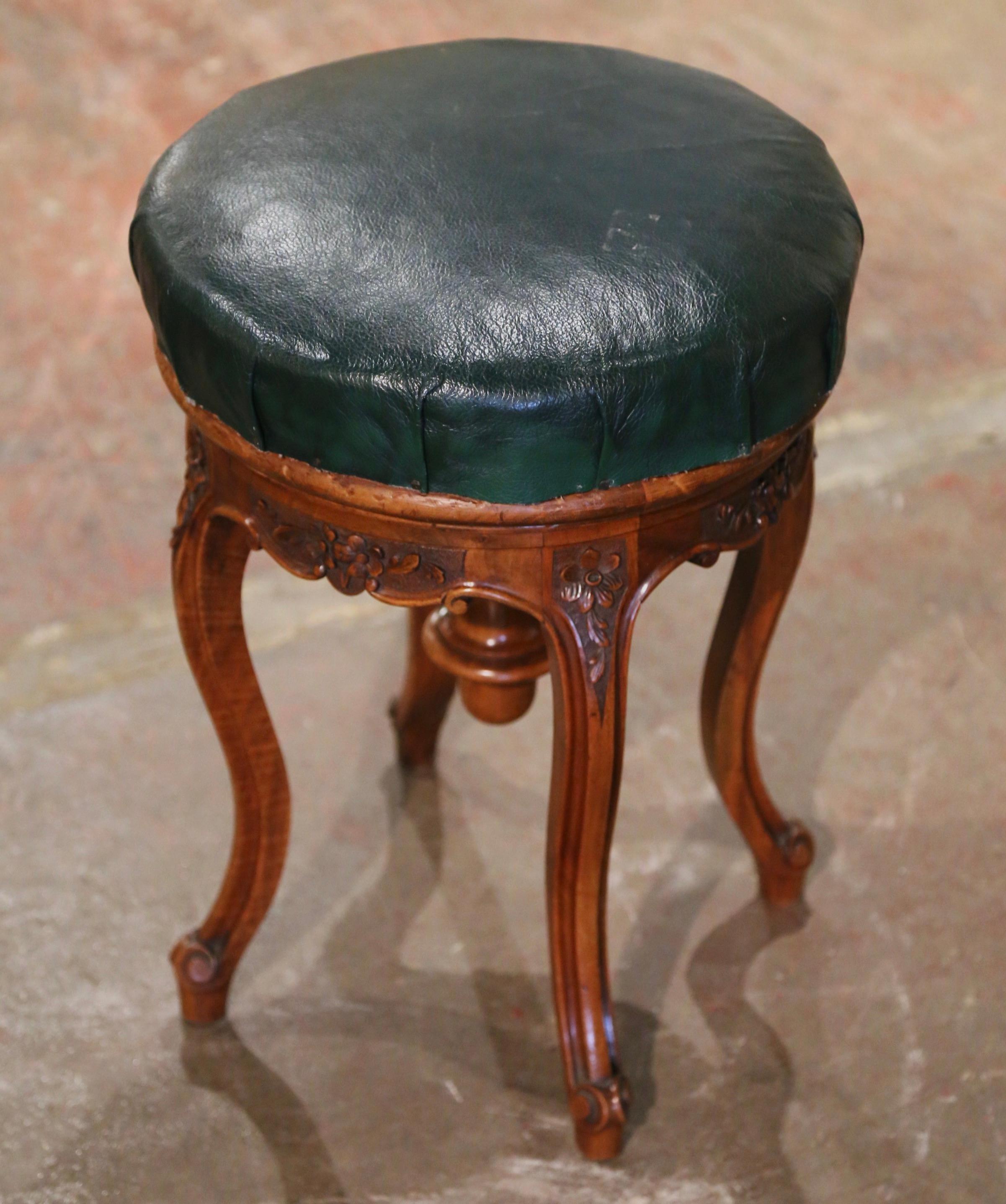 This carved antique fruitwood stool was created in Provence, France circa 1880. Standing on cabriole legs ending with escargot feet, the piano seating is decorated with floral motifs at the shoulders. The round seating is upholstered with a green