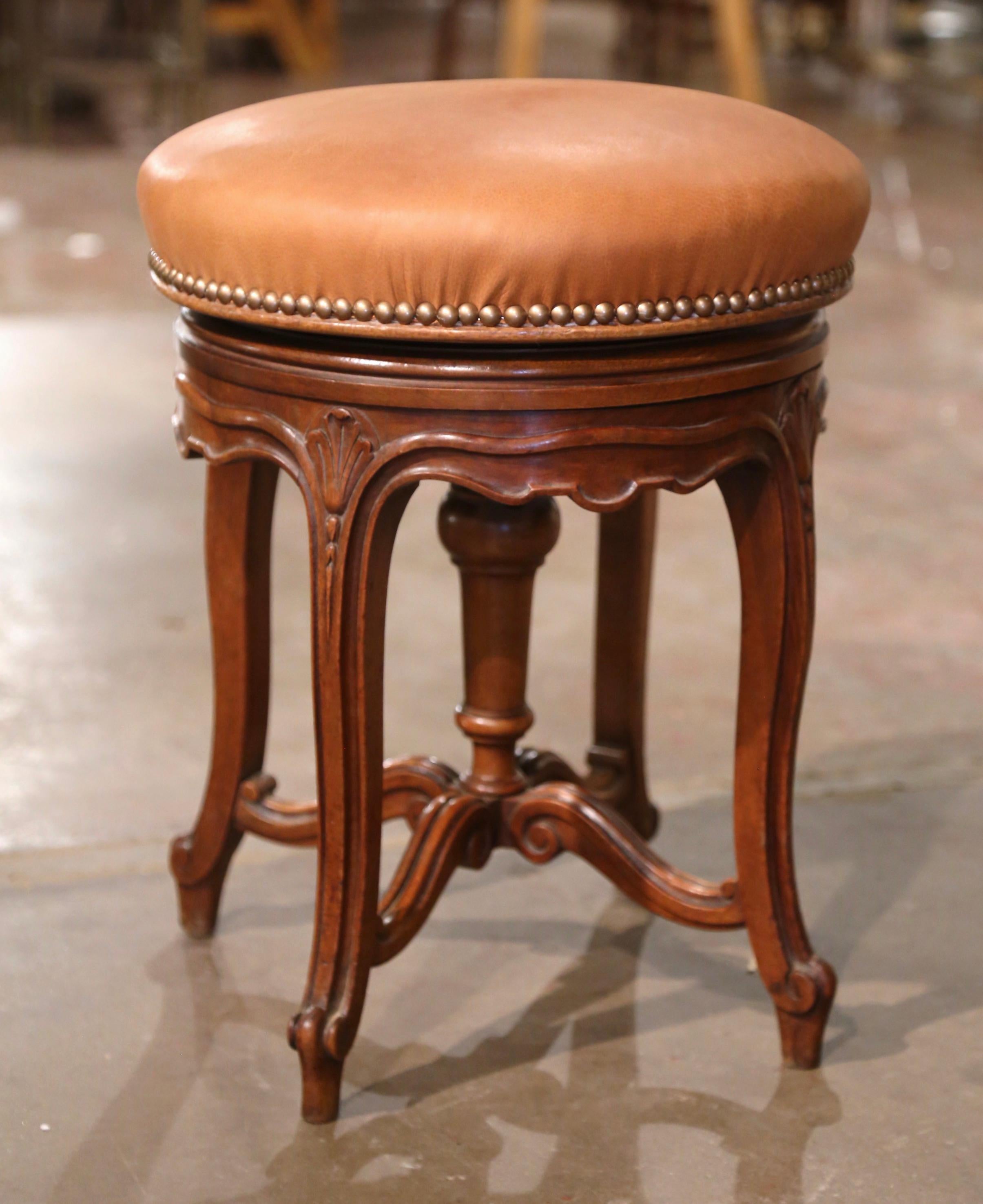 This carved antique fruitwood stool was created in Provence, France circa 1880. Standing on cabriole legs ending with escargot feet, the piano seating is decorated with floral motifs at the shoulders, and is embellished with a bottom stretcher. The