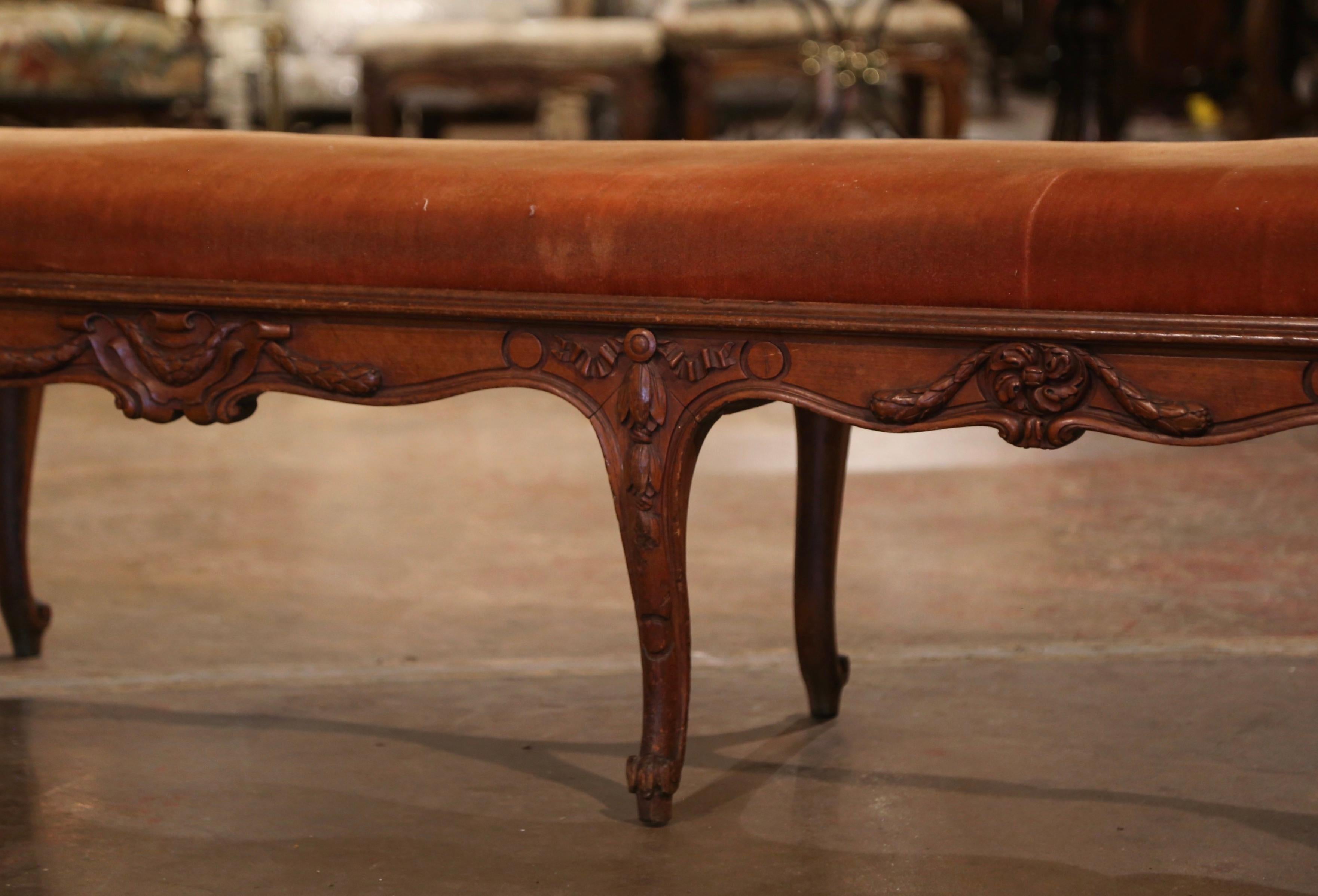 Place this large elegantly carved bench at the foot of a bed, or use it for extra seating in a hallway. Crafted in southern France circa 1880, the antique fruitwood bench stands on eight cabriole legs decorated with leaf motifs at the shoulder and