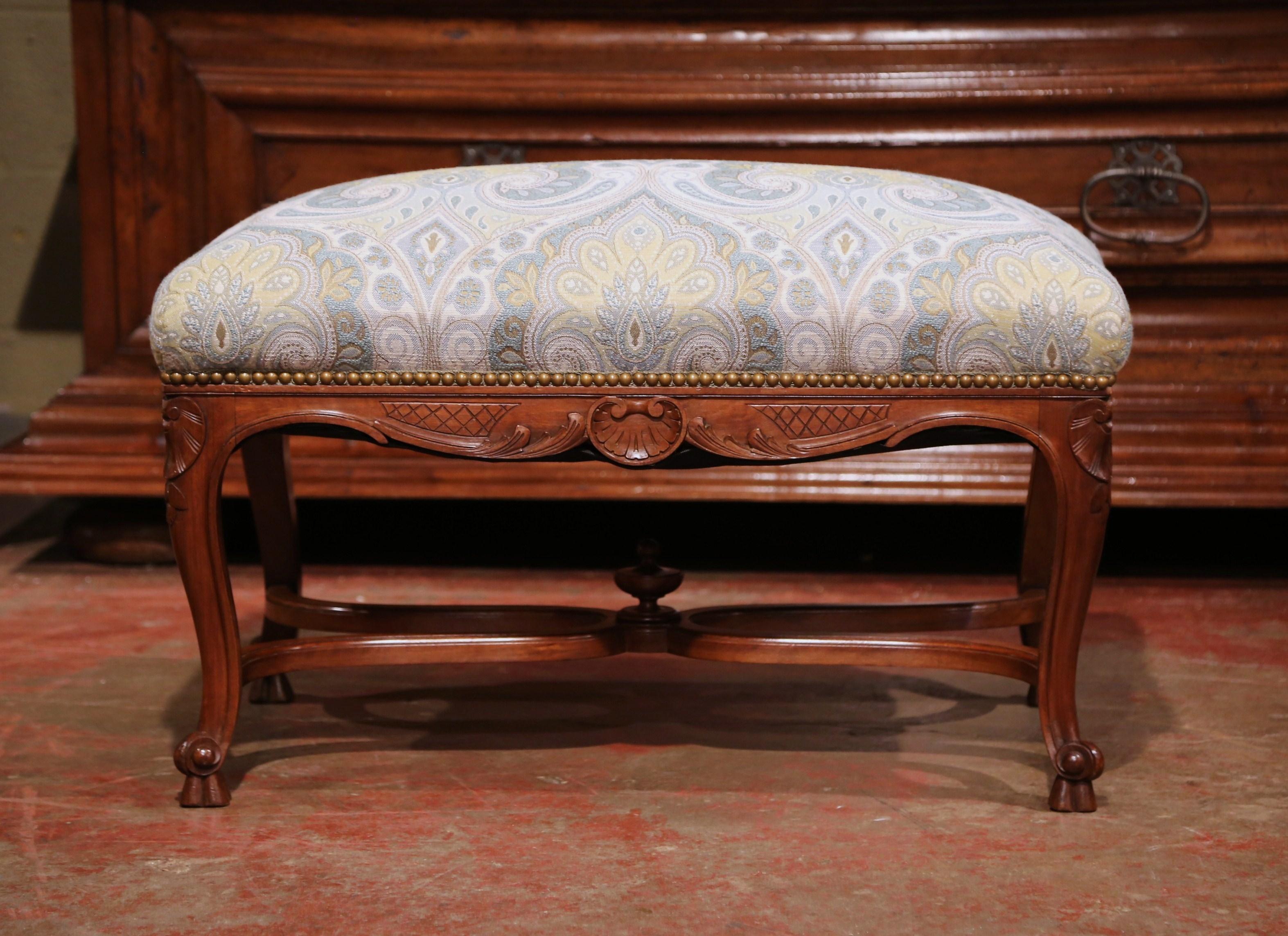 Place this elegant, antique fruitwood bench in your den for extra seating; crafted in Provence, France, circa 1880, the traditional stool features hand-carved shells and foliage decor around the scalloped apron, four cabriole legs with scroll feet,