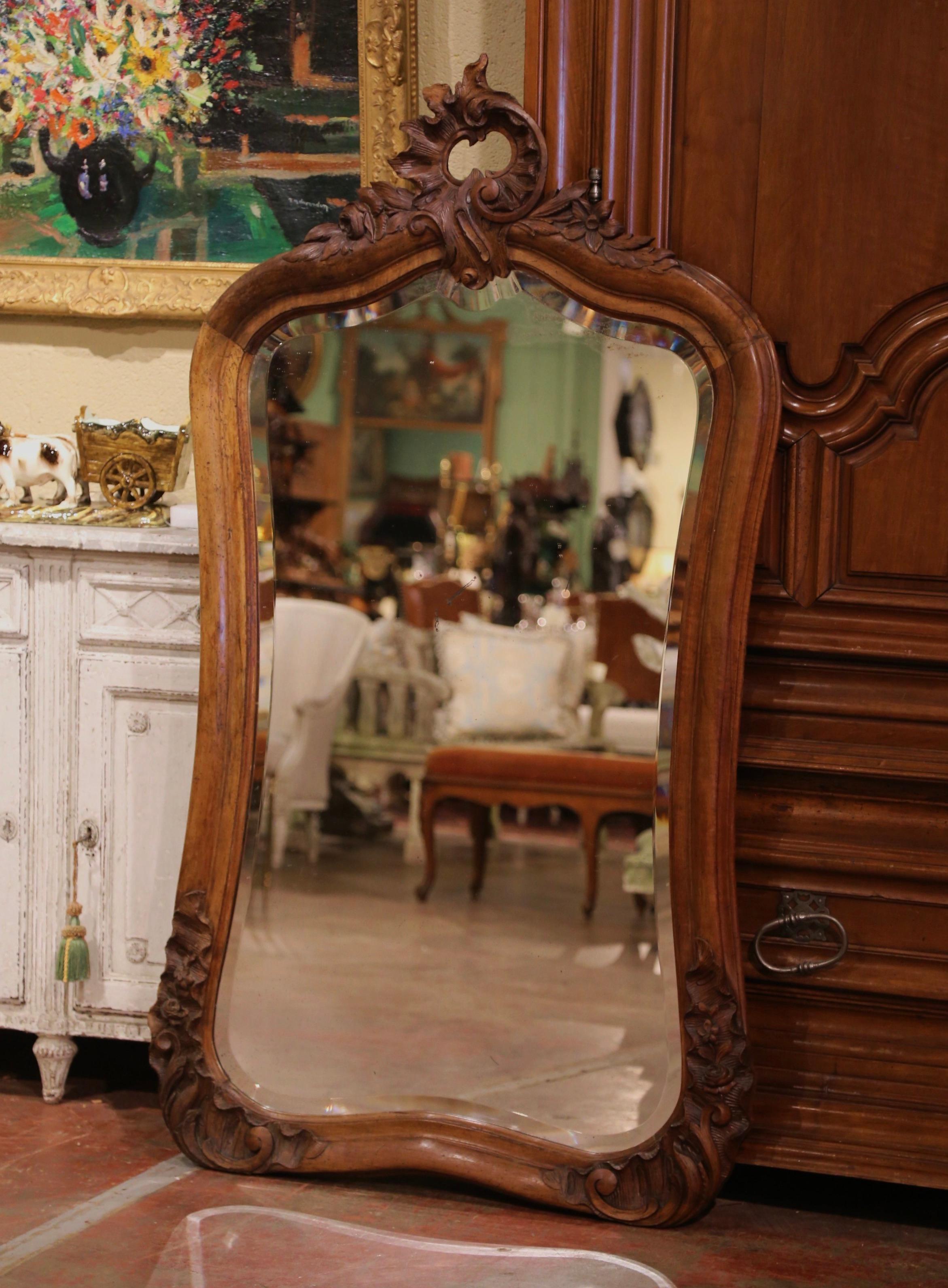 This elegant antique wall mirror was crafted in Southern France, circa 1880. The rectangular mirror with curved sides and bottom, features a nicely carved pierced shell cartouche at the pediment with delicate scroll, leaf and floral motifs. Both