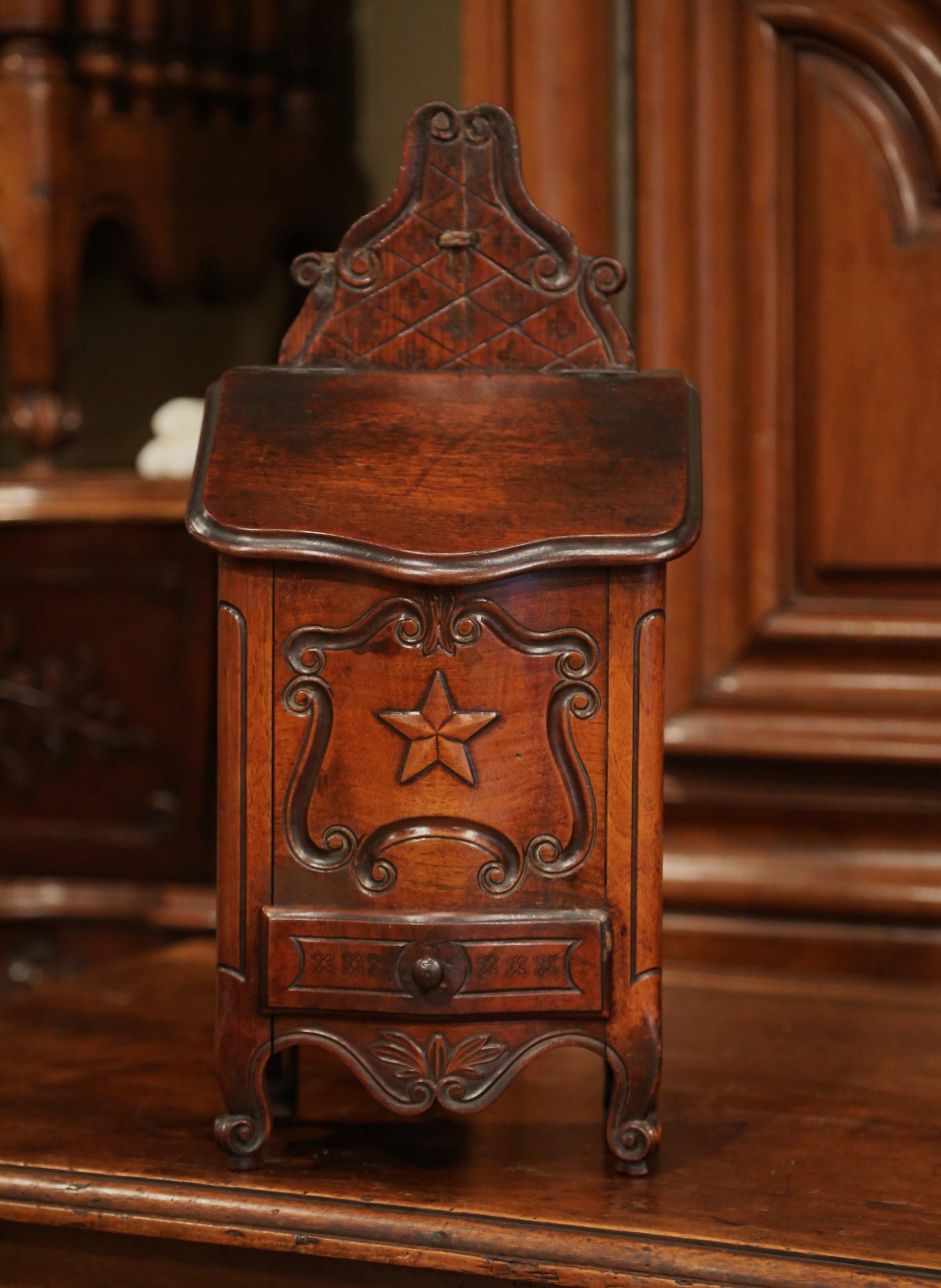This elegant, antique fruitwood salt box was crafted in southern, France, circa 1880. The ornate, decorative, walnut box sits on delicate escargot feet and features beautiful carvings throughout. The bombe box is carved with floral decor on the
