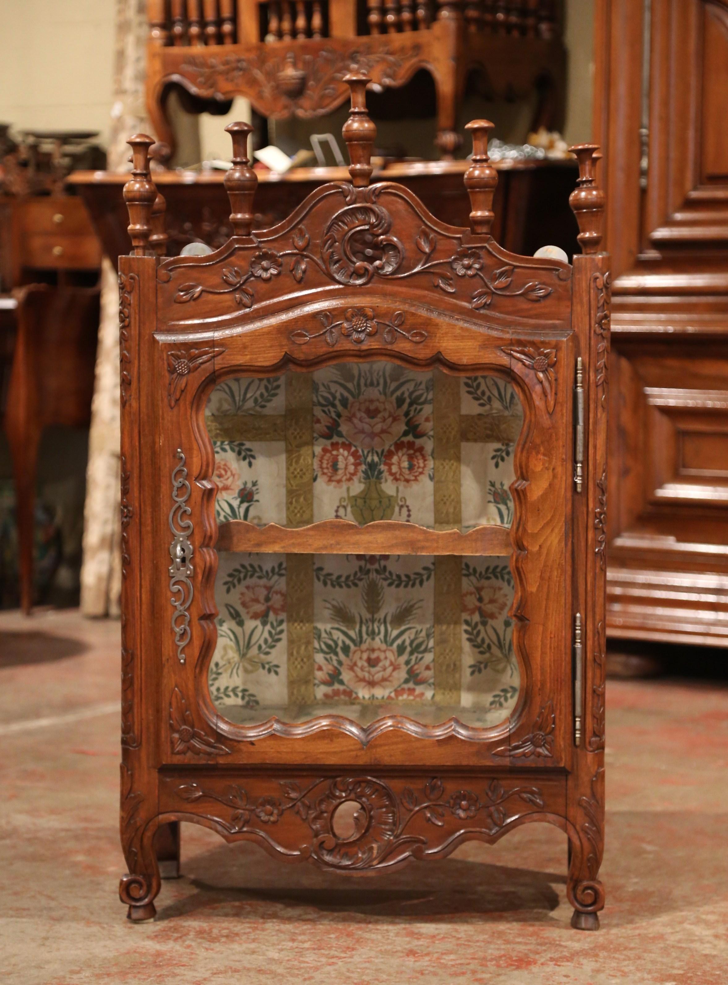 This elegant antique vitrine was crafted in southern France, circa 1880. The petite fruit wood cabinet has a carved and pierced bonnet top embellished with decorative turned finials around the pediment. The vitrine has three sides with clear glass