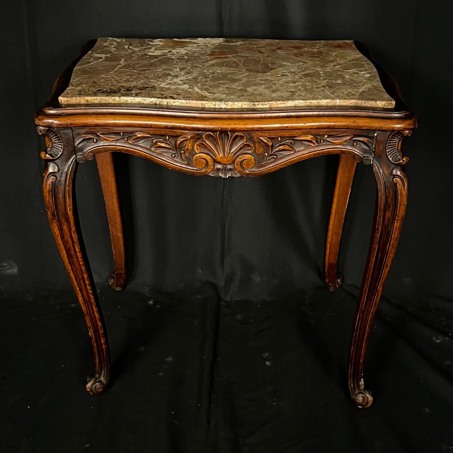 Crafted in France, circa 1880 and rectangular in shape, this antique table stands on cabriole legs ending at scrolled feet. The elegant end table is decorated with delicate hand carved floral and acanthus leaf motifs around the scalloped apron. The