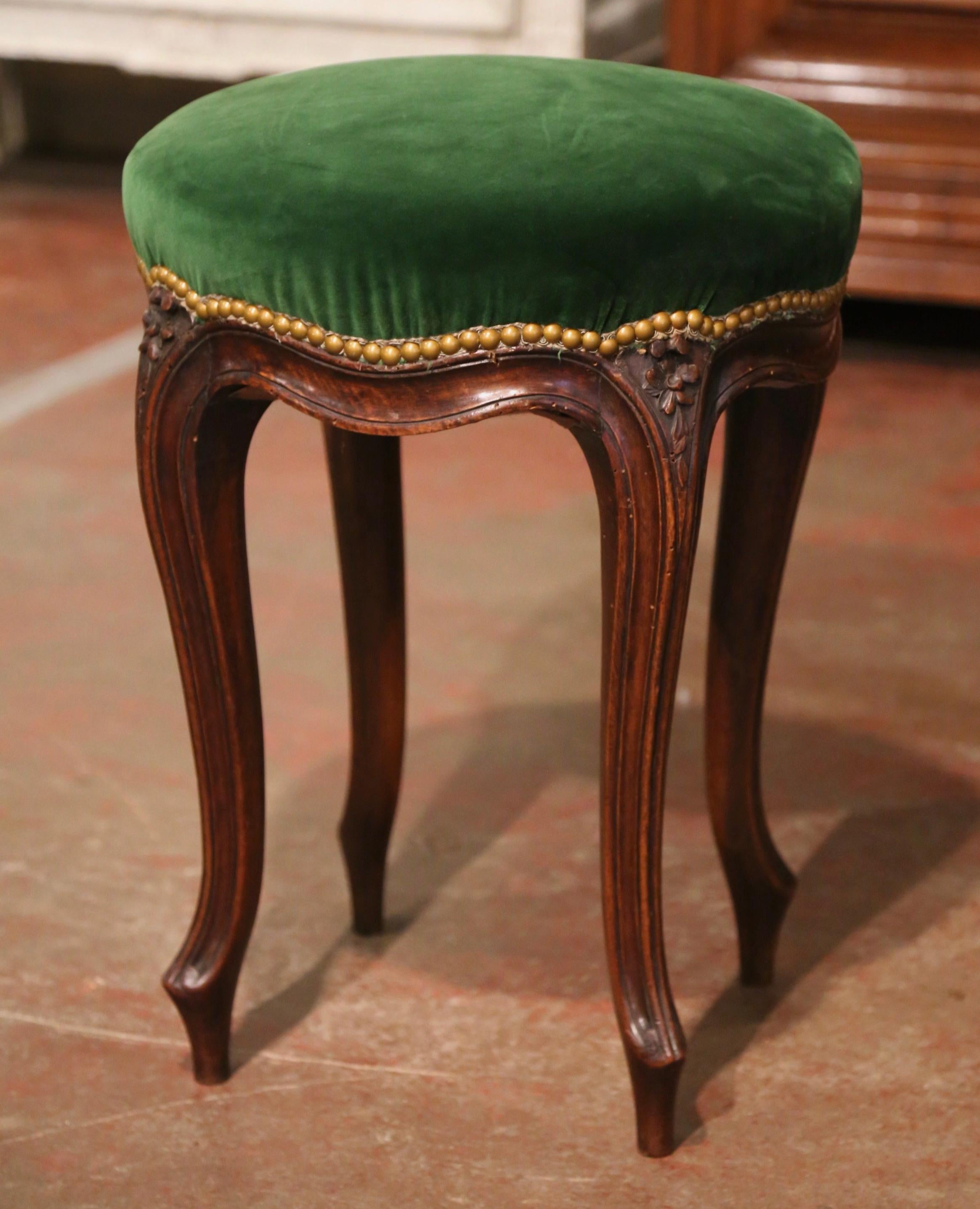 Crafted in southern France circa 1890 and round in shape, the traditional stool stands on cabriole legs decorated with floral motifs at the shoulders, and ending with scrolled feet. The scalloped apron is decorated with simple carvings that extend