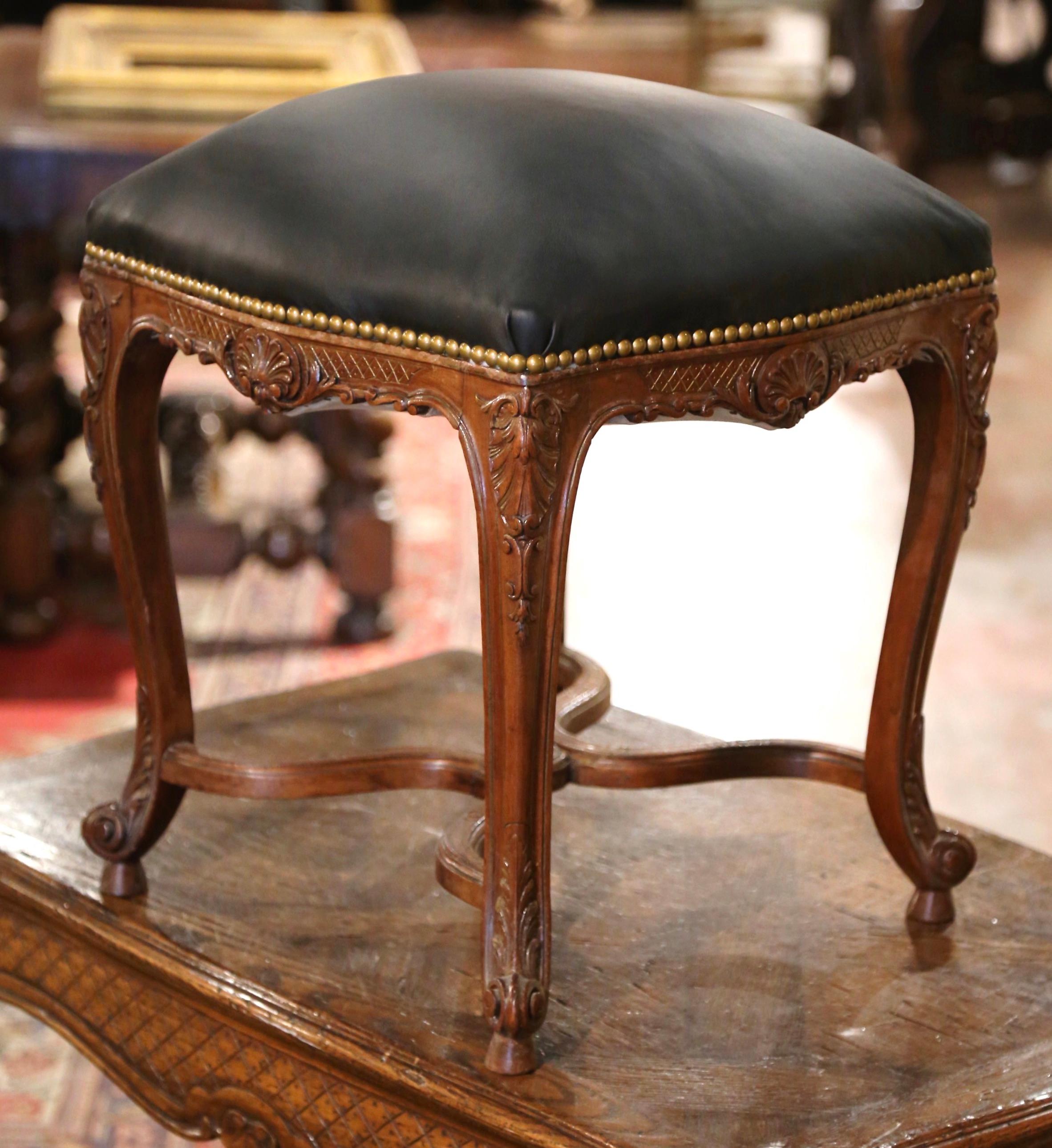 Crafted in southern France circa 1890 and square in shape, the traditional stool stands on cabriole legs decorated with floral motifs at the shoulders, and ending with escargot feet; it is further dressed with a serpentine X stretcher at the base,