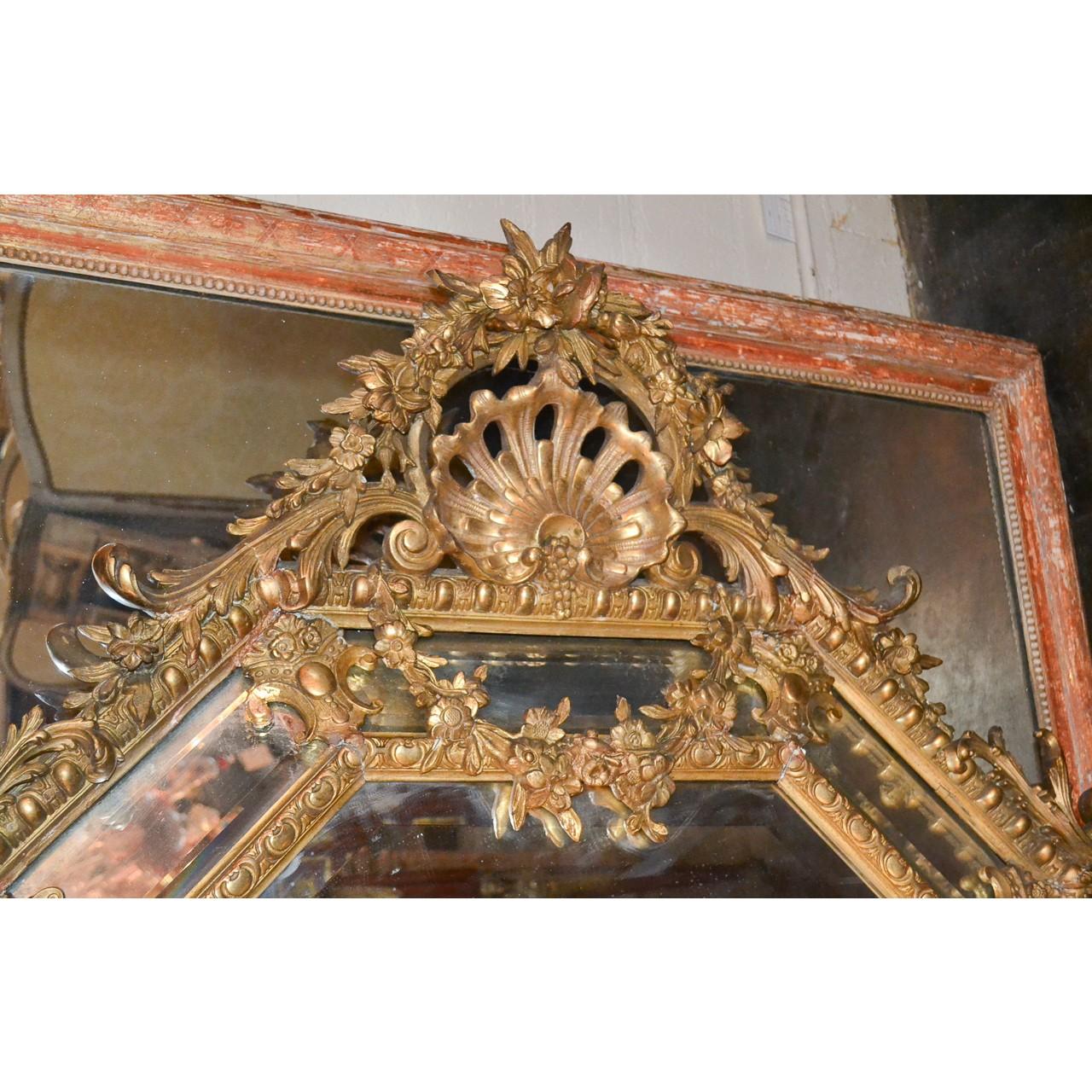 Fine quality large 19th century French Louis XV style cushion mirror with beveled edge and octagonal form. The carved giltwood pediment with trailing floral garland atop a carved shell and festoon swag. The border with finely detailed carved