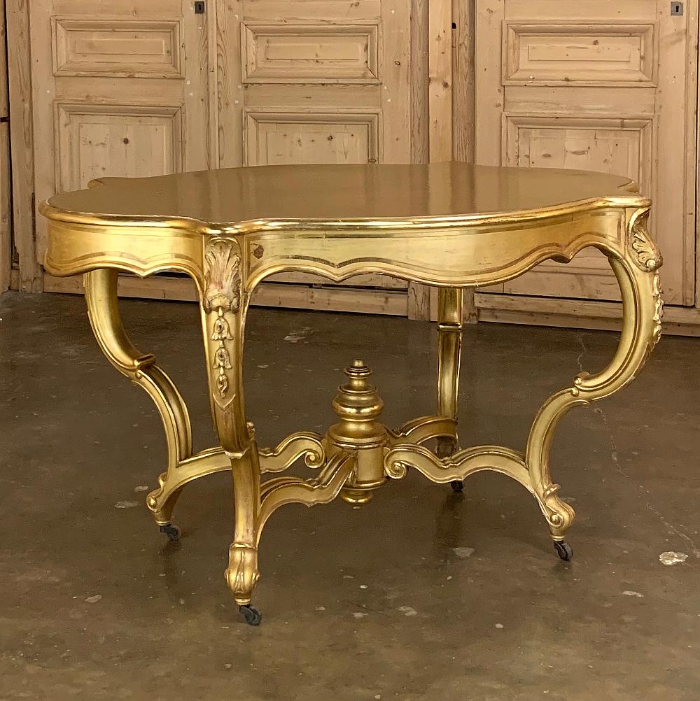 19th century French Louis XV gilded center table is a splendid example of Belle Epoque timeless style! Crafted in a graceful violin shape, its contoured and beveled top rests upon a scrolled apron that is finely molded and trimmed with a French