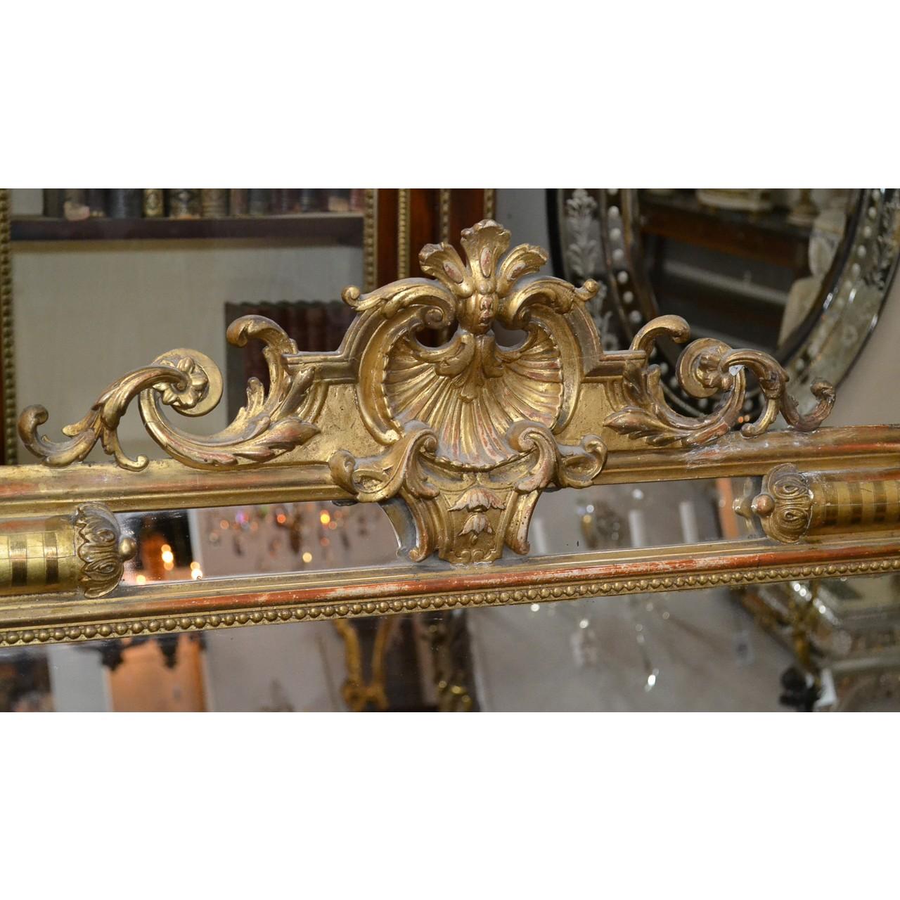 Superb 19th French Louis XV style giltwood wall mirror with an ornately carved crest displaying a large carved shell, flower heads, and scrolling acanthus. The corners with unique convex-shaped accents with leaf crowns. Carved bead inner