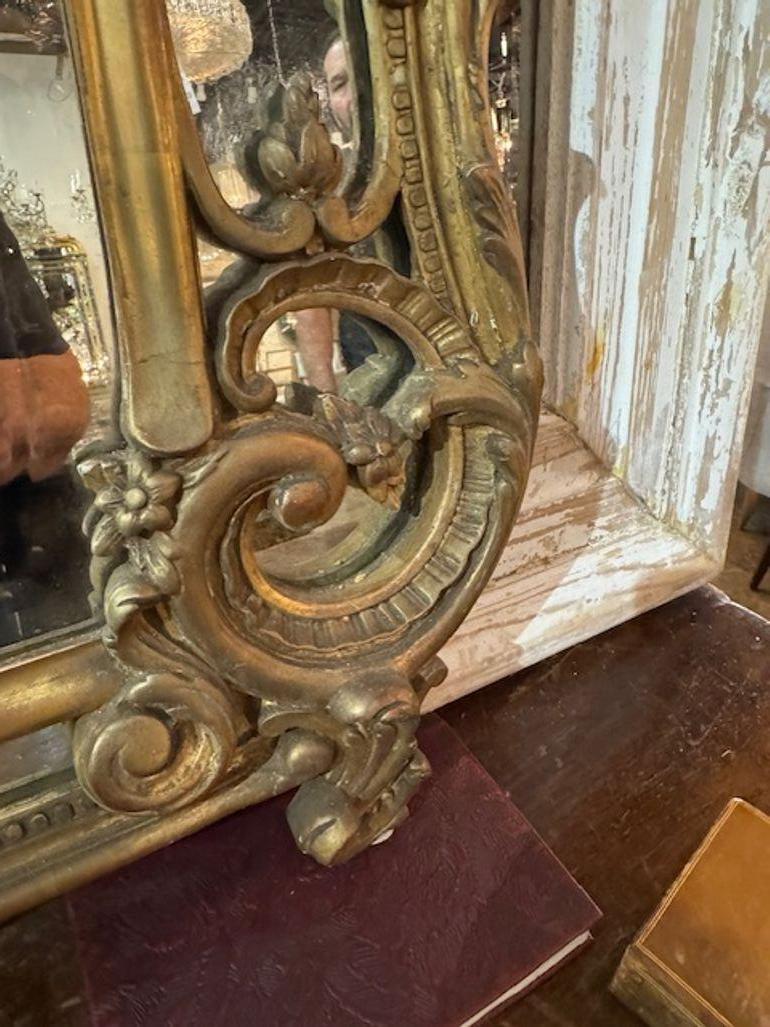 El espejo francés Luis XV de madera dorada del siglo XIX es un mueble exquisito que desprende elegancia y sofisticación. La madera dorada tallada  marco  añade un toque de lujo a cualquier habitación en la que se coloque. Este espejo antiguo es una