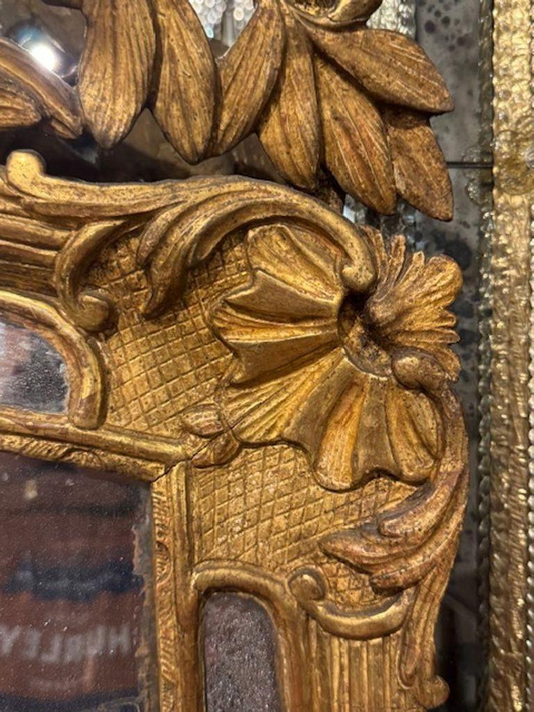 Ce miroir en bois doré Louis XV du XIXe siècle présente une belle sculpture et une magnifique patine dorée. Cette pièce ajoute une touche d'élégance à n'importe quelle pièce. Le design complexe et l'artisanat du miroir reflètent l'art du style