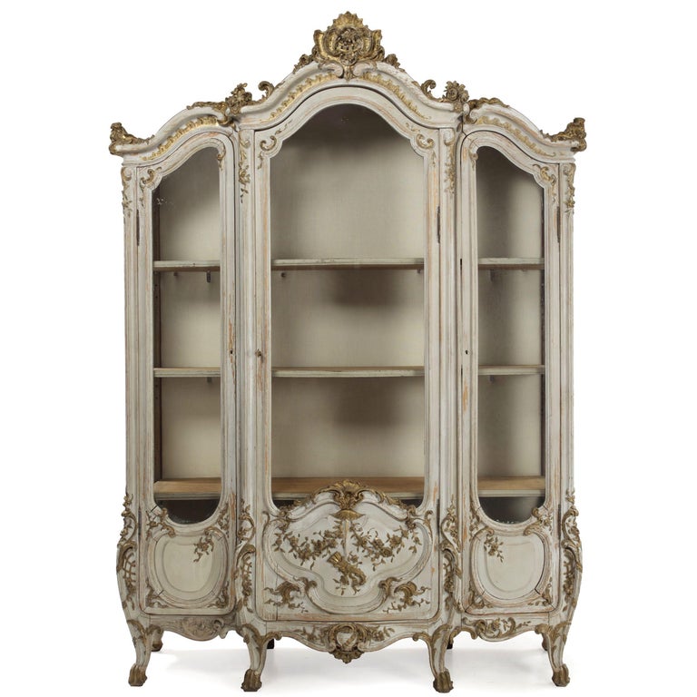 An incredibly fun and playful display cabinet in the Rococo taste with a distinctively Venetian flare, this positively gorgeous cabinet retains an early gray painted finish that is beautifully worn throughout. Probably circa the first quarter of the