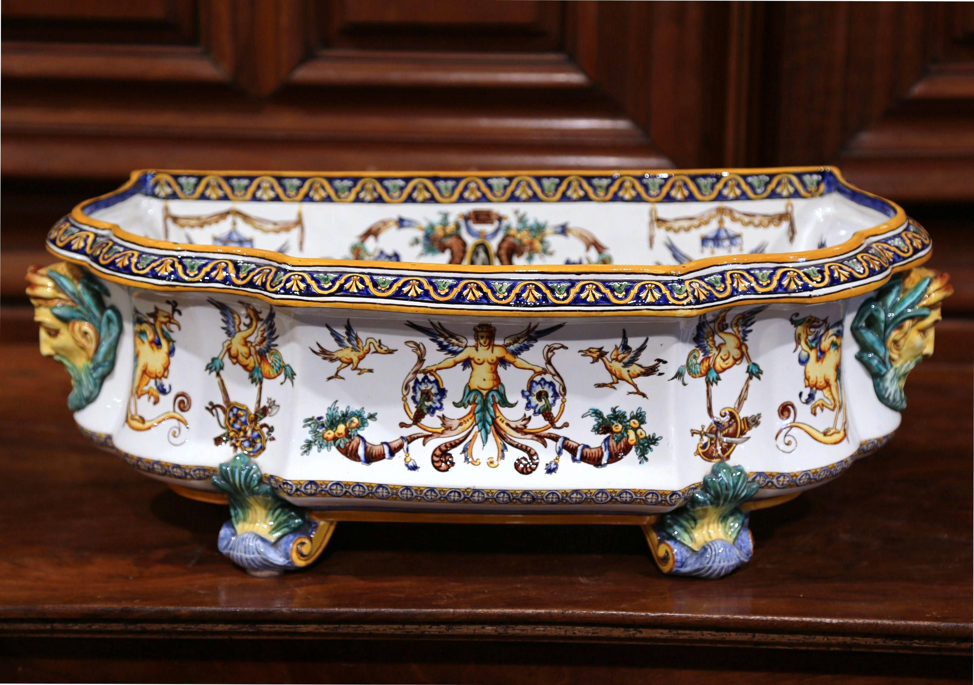 This long colorful antique planter was created in the “Faïencerie de Gien”, France, circa 1890. The large demilune shape ceramic jardinière sits on four curved feet. The planter features Greek face handles and is decorated with hand painted