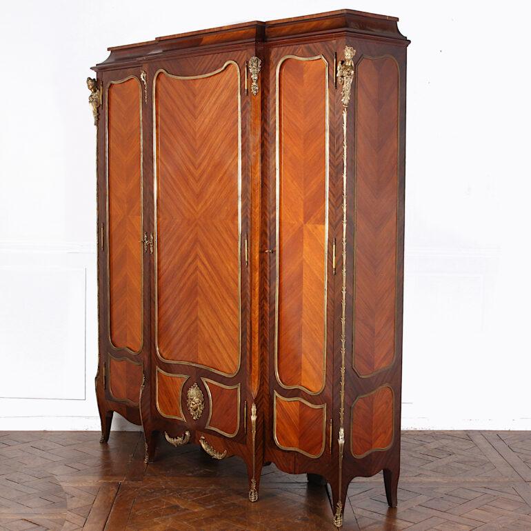 A most impressive French late-19th century Louis XV breakfront armoire, the doors and panels with mahogany edges and book-matched kingwood centre panels, and accented throughout with finely cast and finished gilt bronze mounts. The figural corner