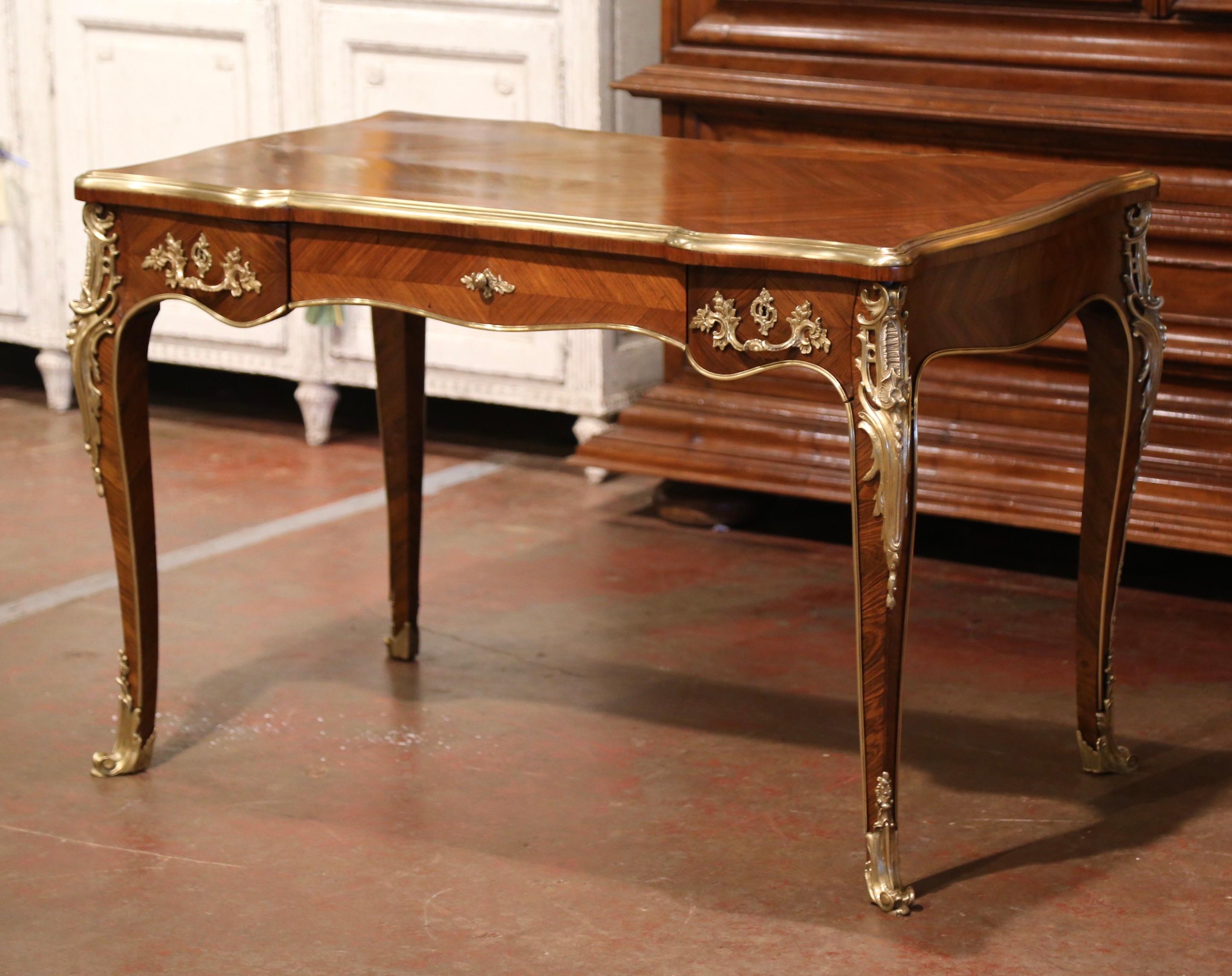 This elegant antique table was crafted in France, circa 1870. Bombe in shape, the fruit wood writing table stands on cabriole legs decorated by large bronze dore acanthus leaves mounts at the shoulders, and terminating with gilt bronze sabot feet.
