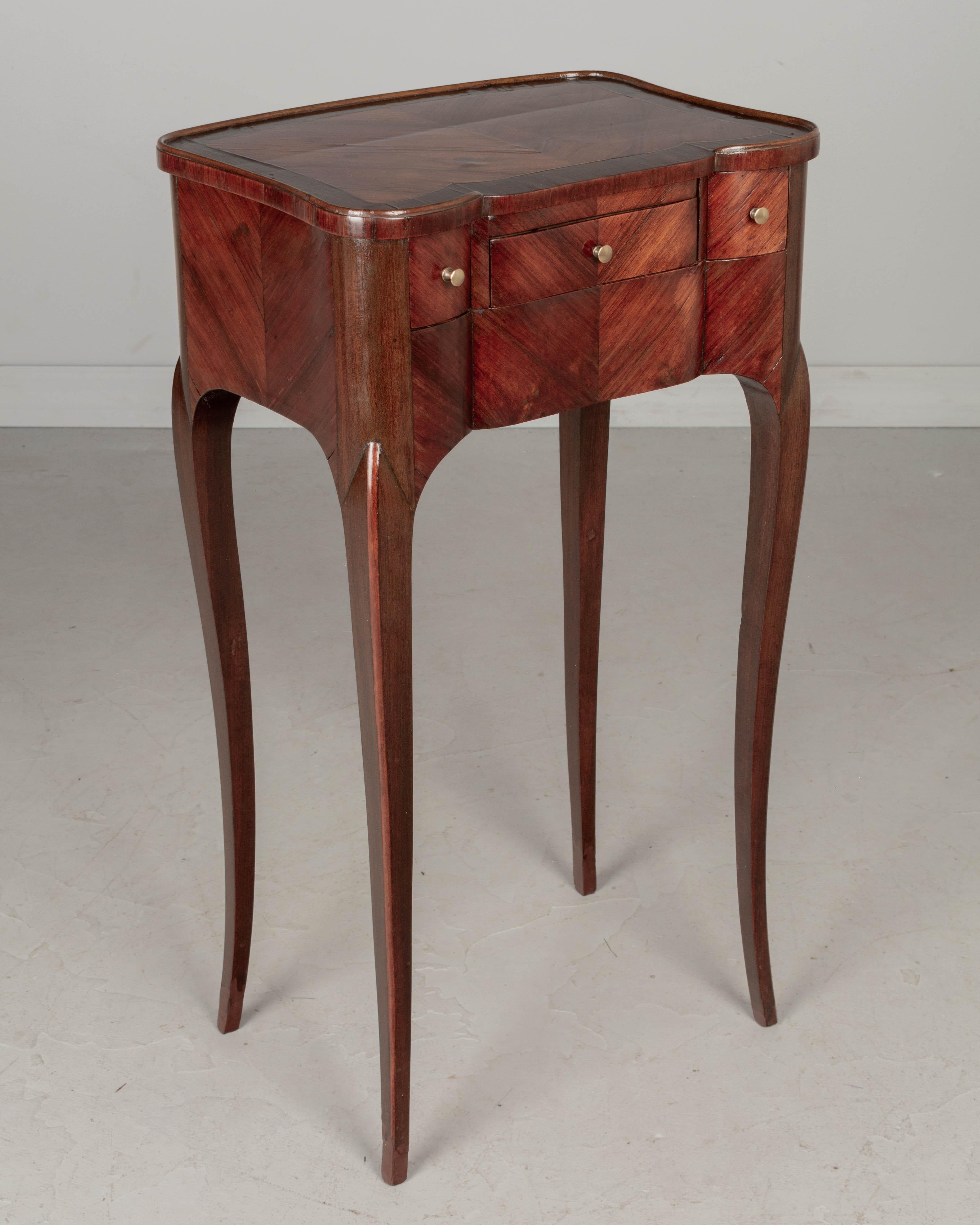 A fine 19th Century French Louis XV style marquetry side table made of bookmatched veneers of rosewood and tulipwood. Elegant proportions with tall slender legs, curved sides and shaped front. Pull-out leather writing surface or book stand that may