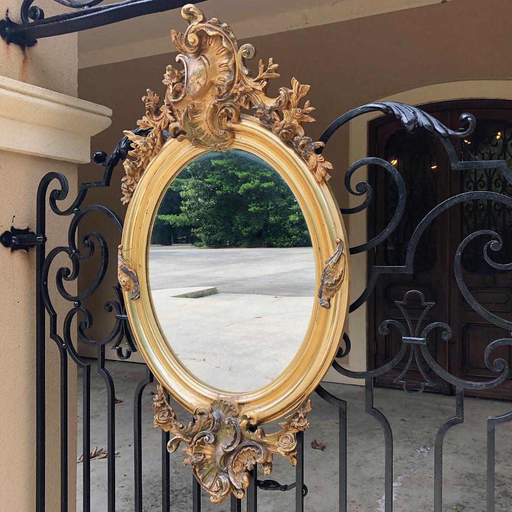 19th century French Louis XV oval gilded mirror is the perfect choice to add style, flair, visual excitement, and a lovely reflection of ambient light! Exuberant Rococo-inspired crown features stylized shell, floral and foliate motifs that envelope