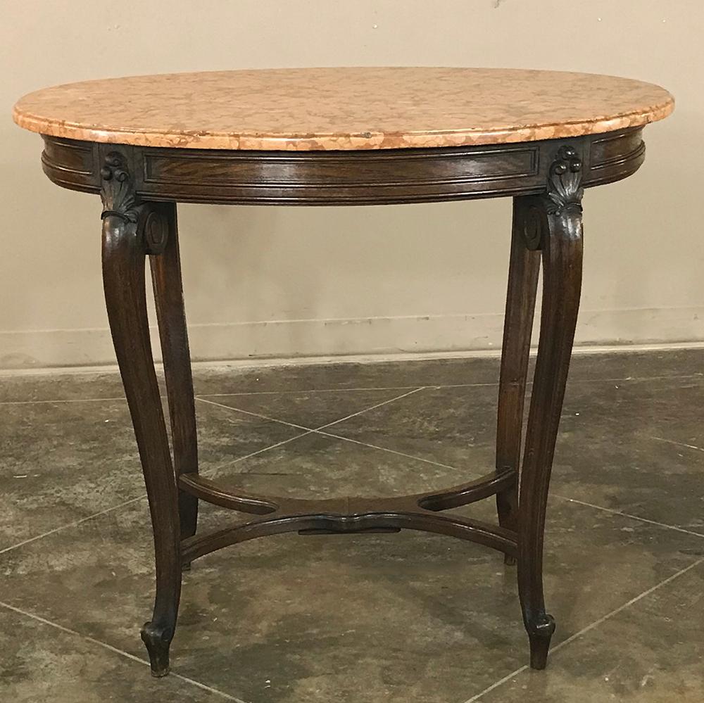 19th century French Louis XV oval marble top end table features tailored lines somewhat unusual for the genre, with subtly scrolled legs connected by double-bowed stretchers. A slight touch of carved detail appears above the legs which are scrolled