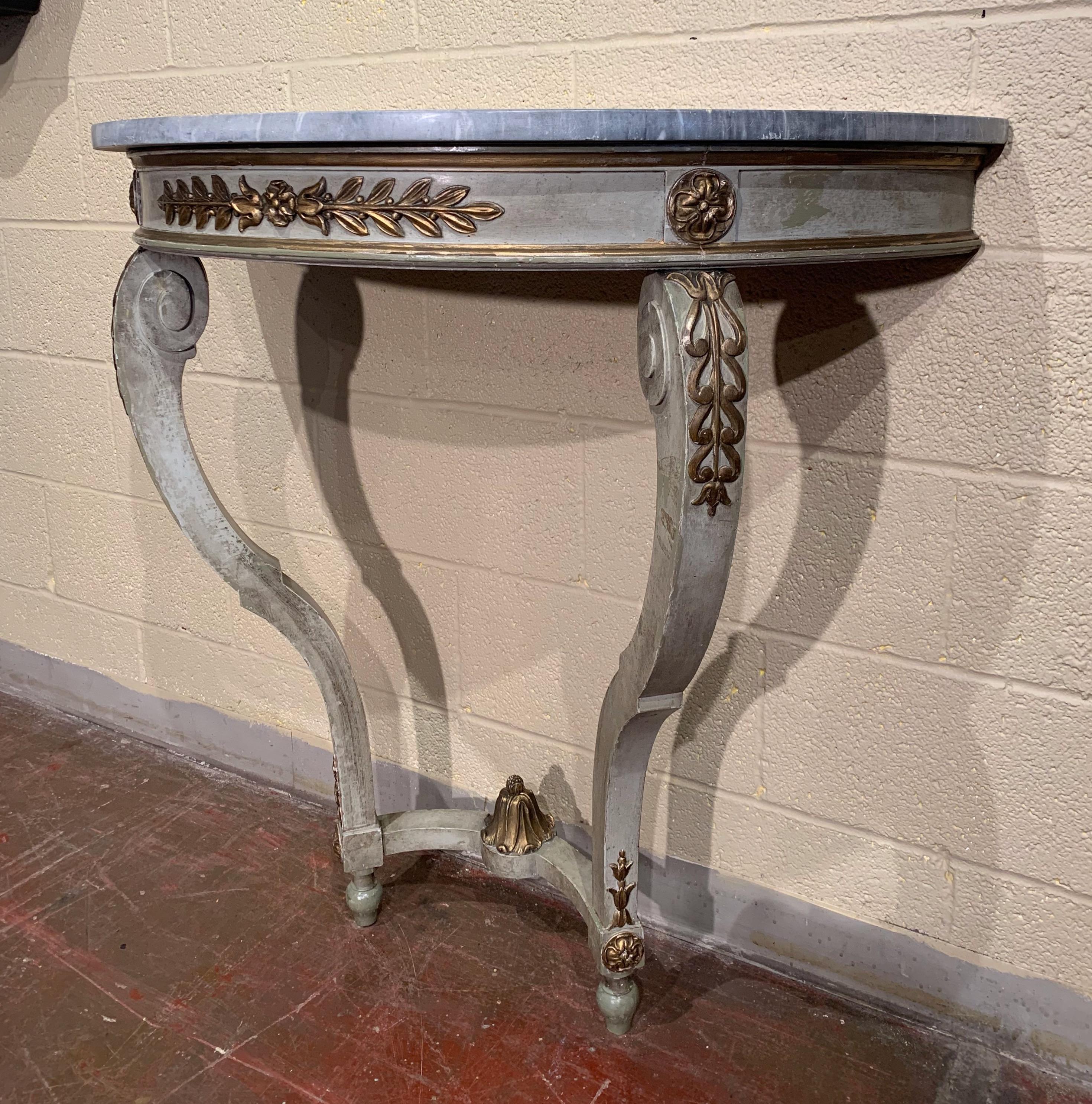 This antique painted console was crafted in France, circa 1860; shaped as a half moon and standing on cabriole legs decorated with acanthus leaves, the table features foliage carving on the bombe apron and embellished with floral medallions in the
