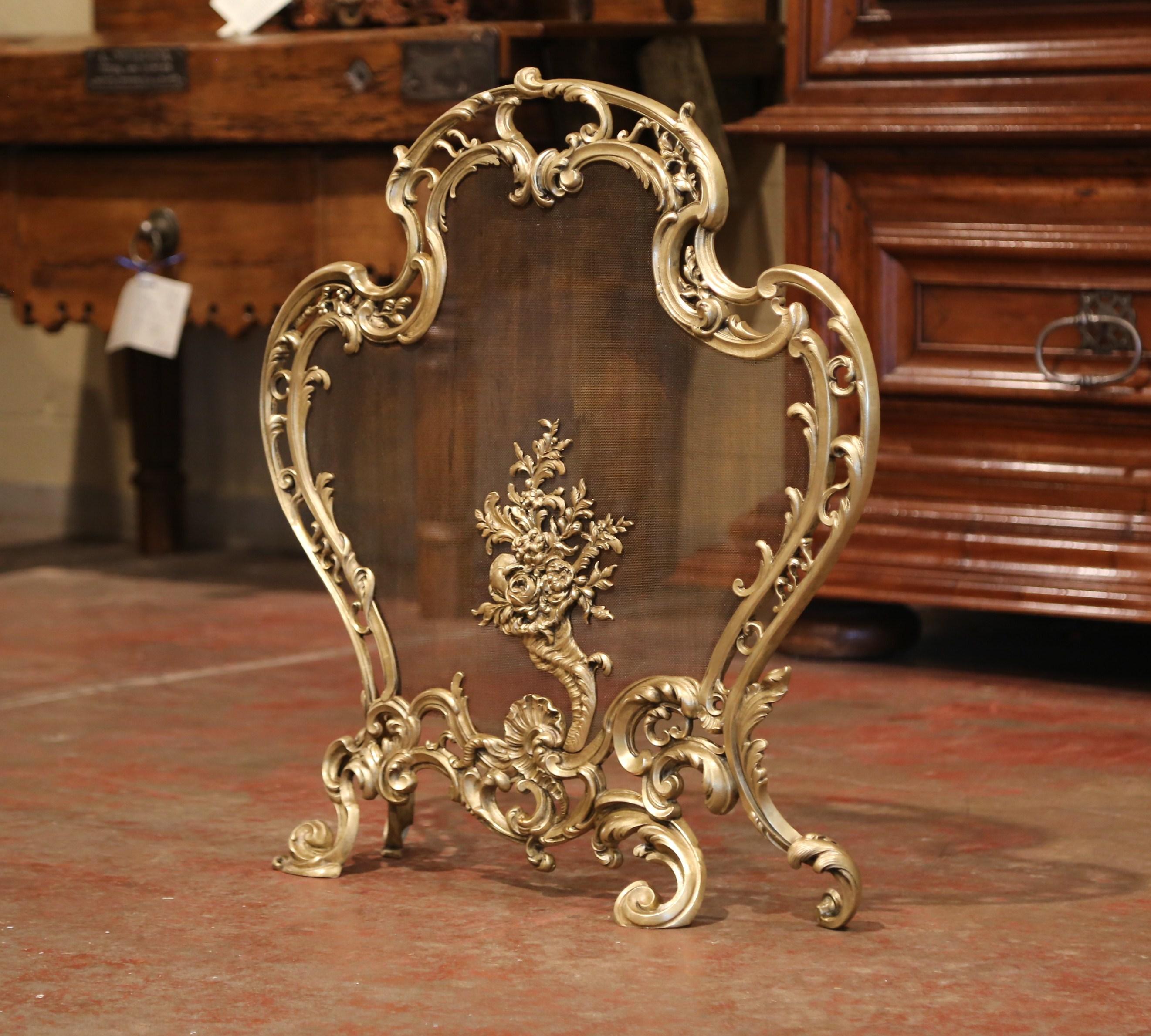 Decorate your fireplace with this antique bronze screen; crafted in France circa 1870, the cartouche shaped screen sits on four scrolled feet and features Louis XV style motifs including asymmetrical foliage swaths, and a center medallion with