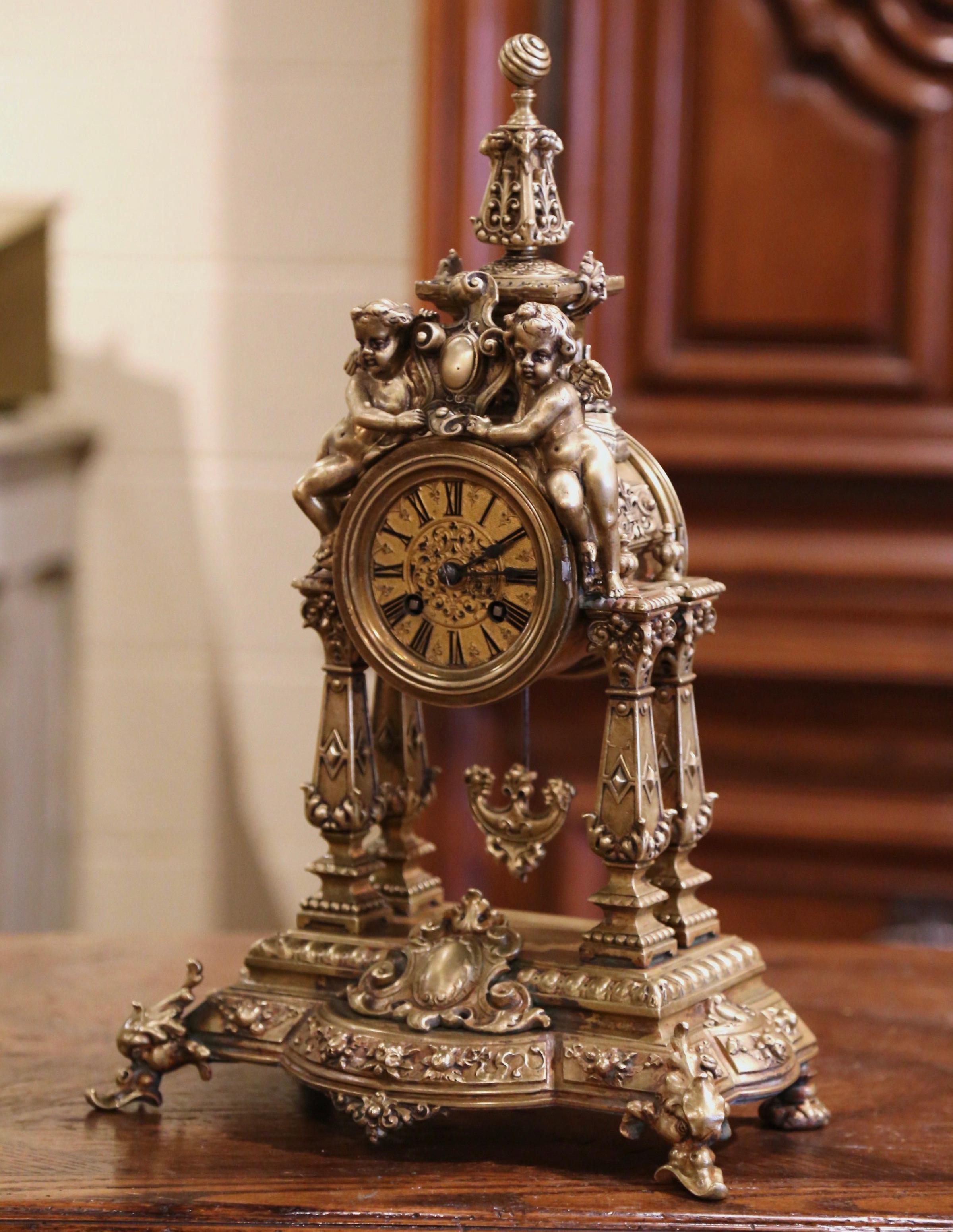 Crafted in Paris, France circa 1860, the antique time keeper stands on an attached ornate base over scrolled feet; the portico clock with side columns and decorative top finial is decorated with two cherubs holding a shield. The clock is further